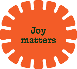 Orange circular badge with jagged edges and the words 'Joy matters' in black text in the center.
