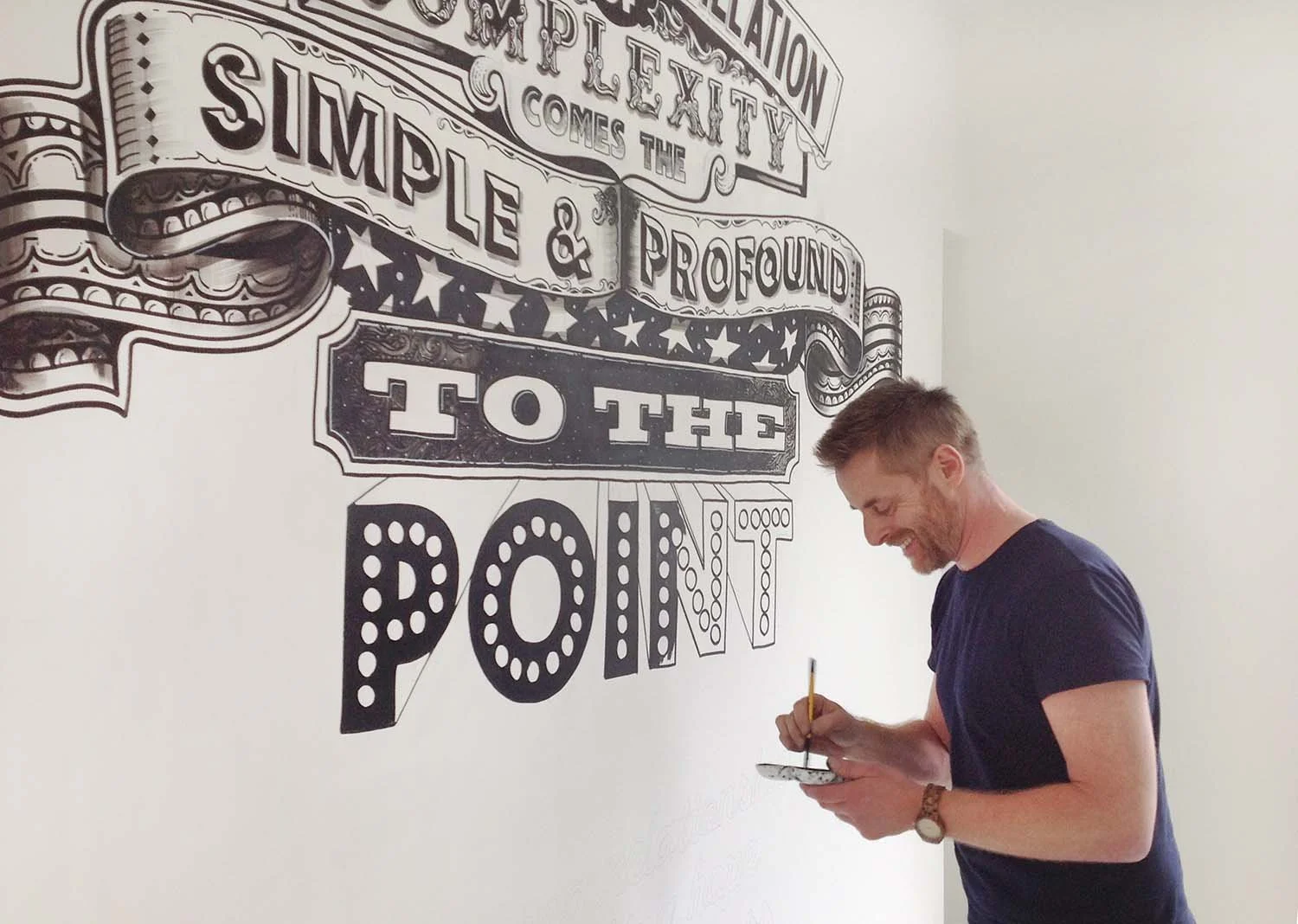 Vic Lee hand painting a large-scale typography mural in London