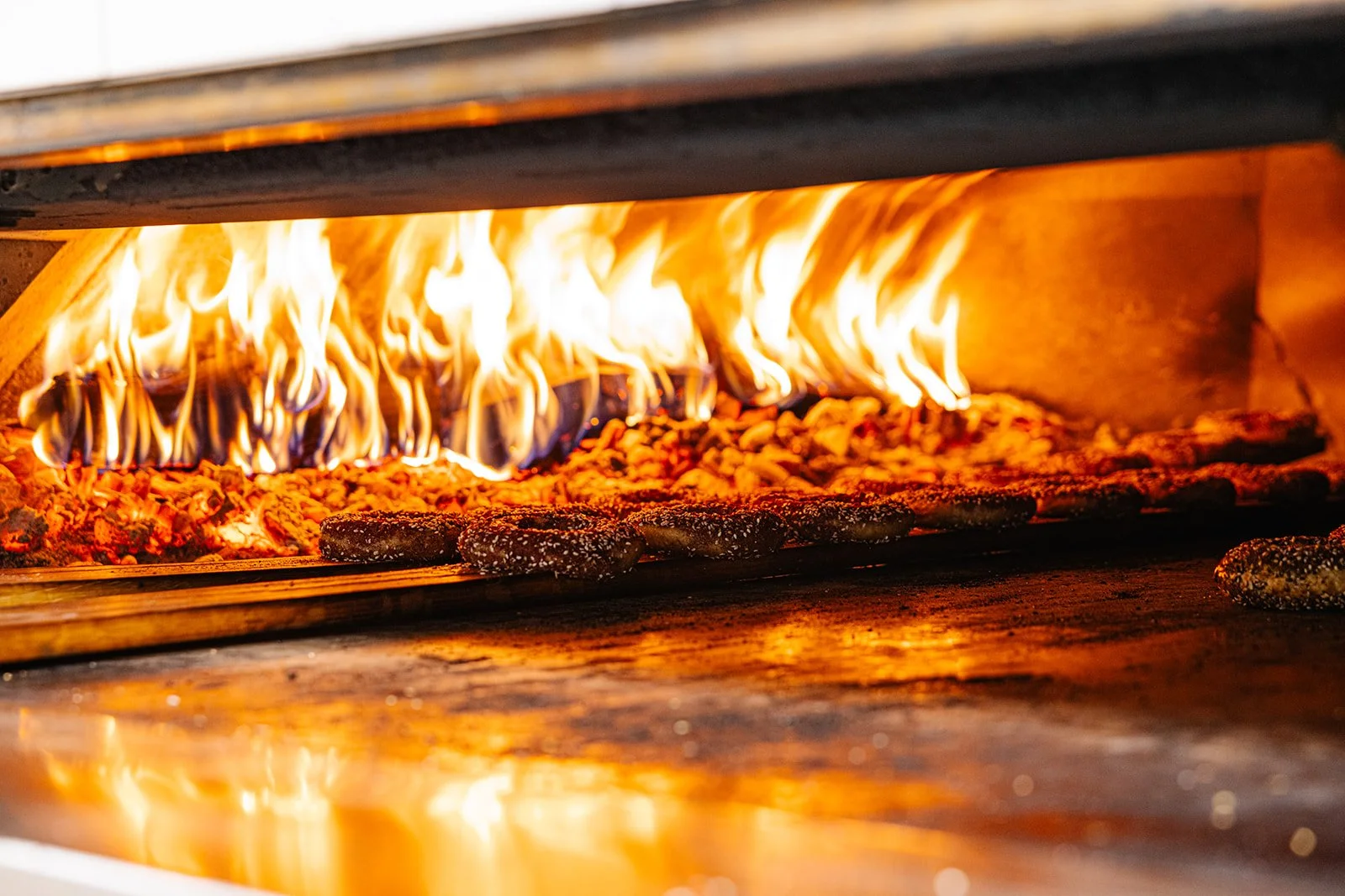 Our wood-fired oven, flames ablaze, with several bagels cooking inside.