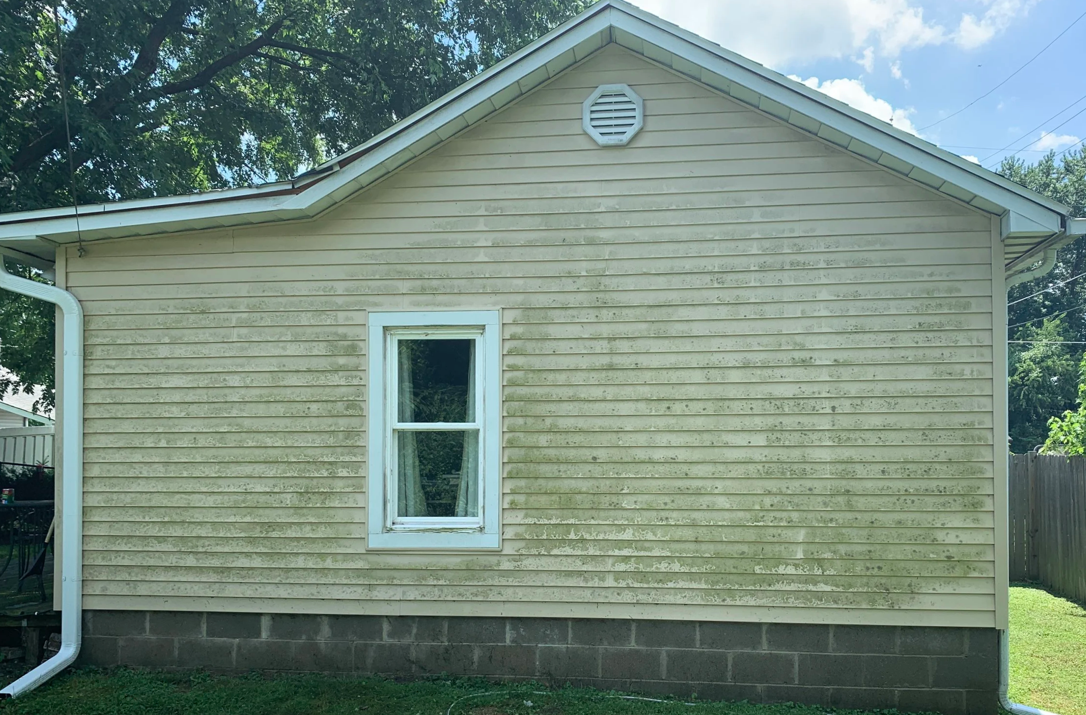 Before: This Bloomington, Indiana home’s vinyl siding had built-up dirt, algae, and organic growth that dulled its appearance. Professional exterior cleaning with a softwash process was needed to safely restore the home's curb appeal.