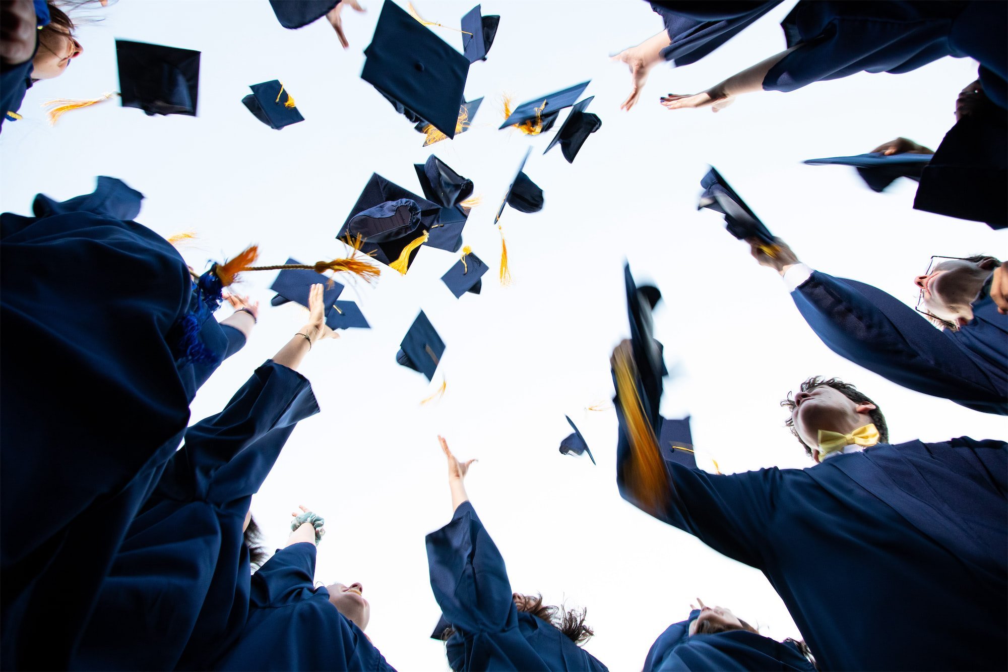 Graduates in caps and gowns tossing their caps into the air during a graduation ceremony.