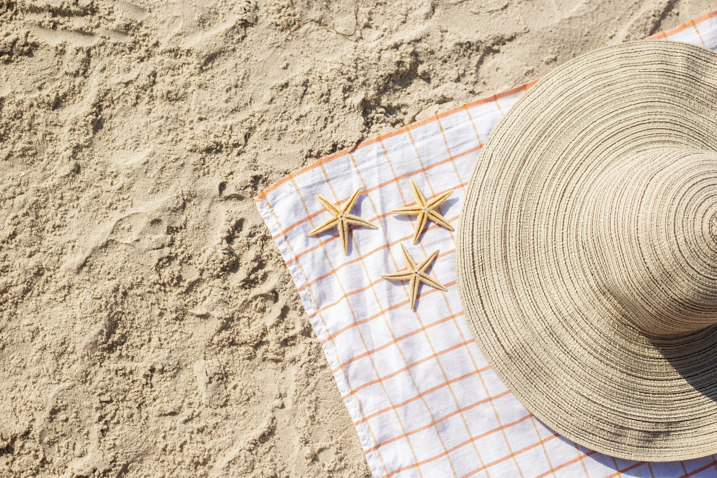 Sun hat and starfish on beach blanket on the beach.