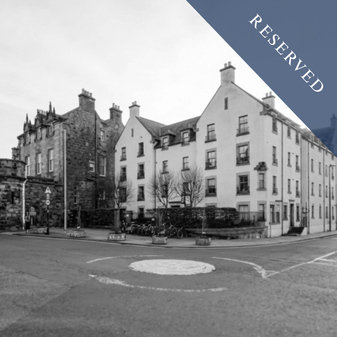 Black and white photo of residential buildings with a small parking area in front, trees, and bicycles, with a 'Reserved' banner overlay in the top right corner.