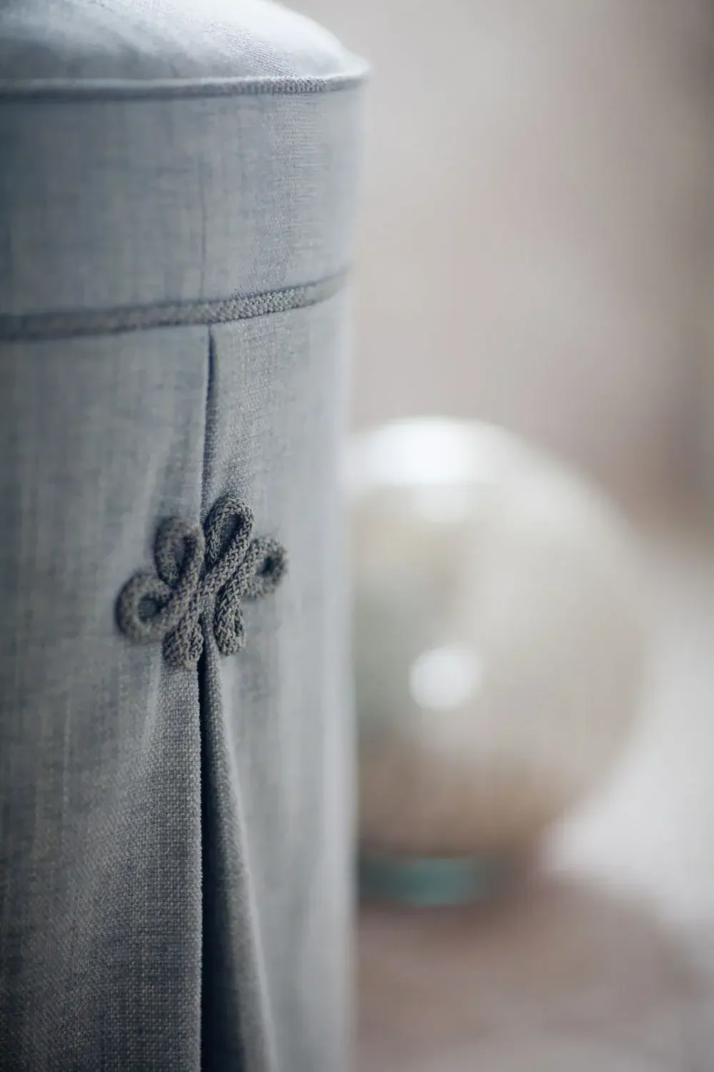 Close-up of a fabric storage box with a decorative knot on front, made of grey material.