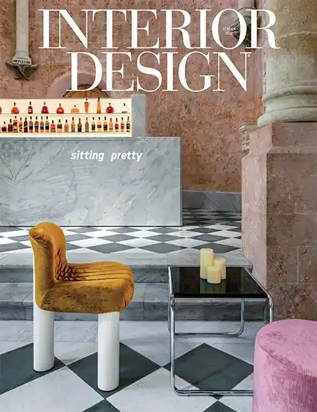 Interior of a stylish bar or lounge with a marble bar counter, checkered floor, and modern chairs, including a yellow velvet chair and a pink seat. Candles are on a glass table, and shelves of liquor bottles are in the background.
