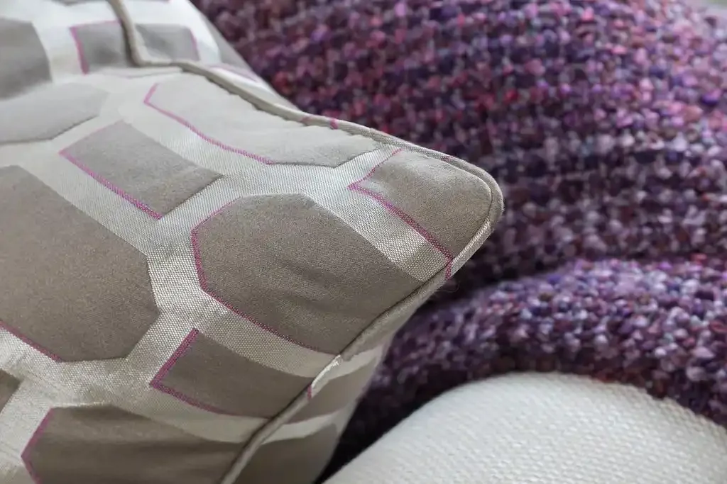 Close-up of a decorative pillow with a geometric pattern on a purple textured couch.