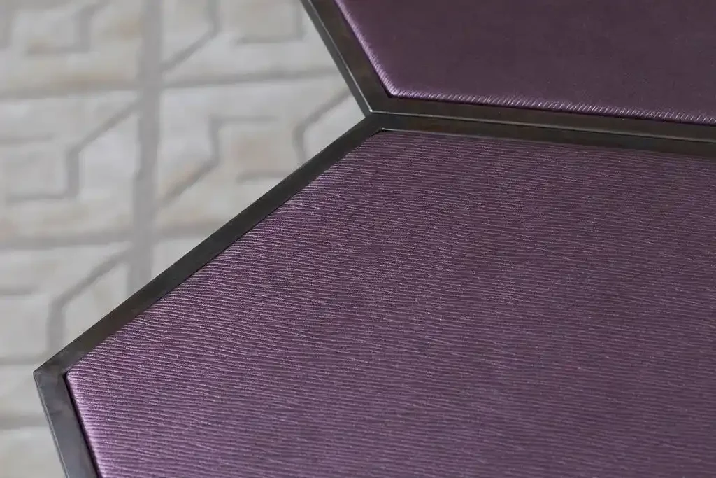 Close-up of a purple textured book cover or box with black edges, open against a blurred patterned background.