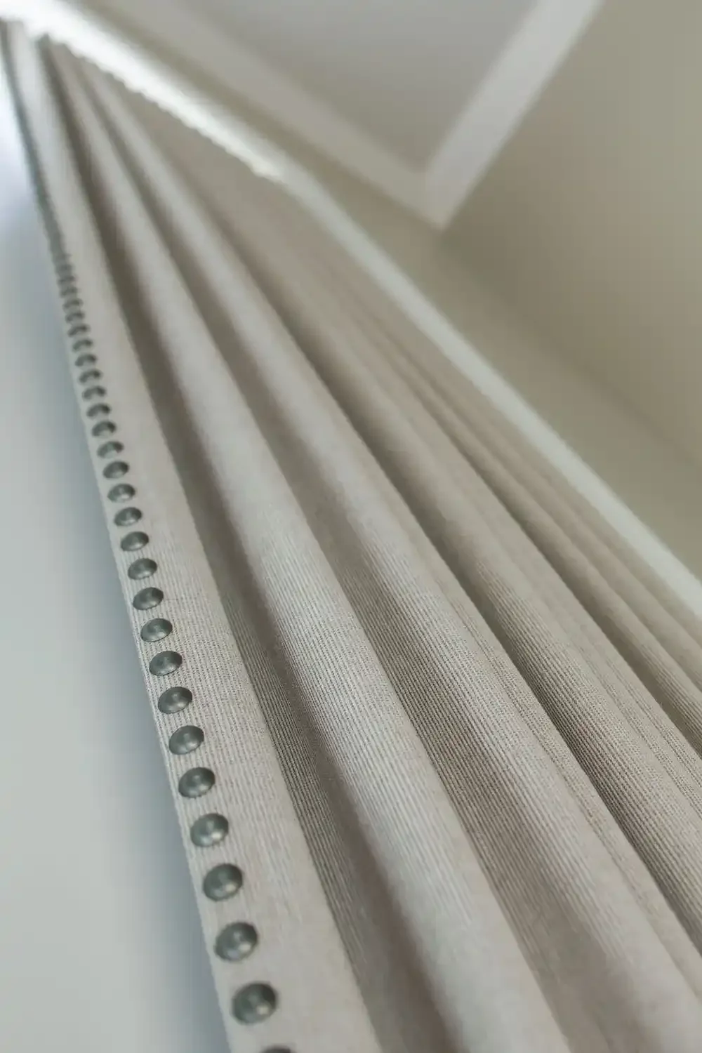 Close-up of a metal perforated strip with evenly spaced holes, attached to a surface with vertical grooves.