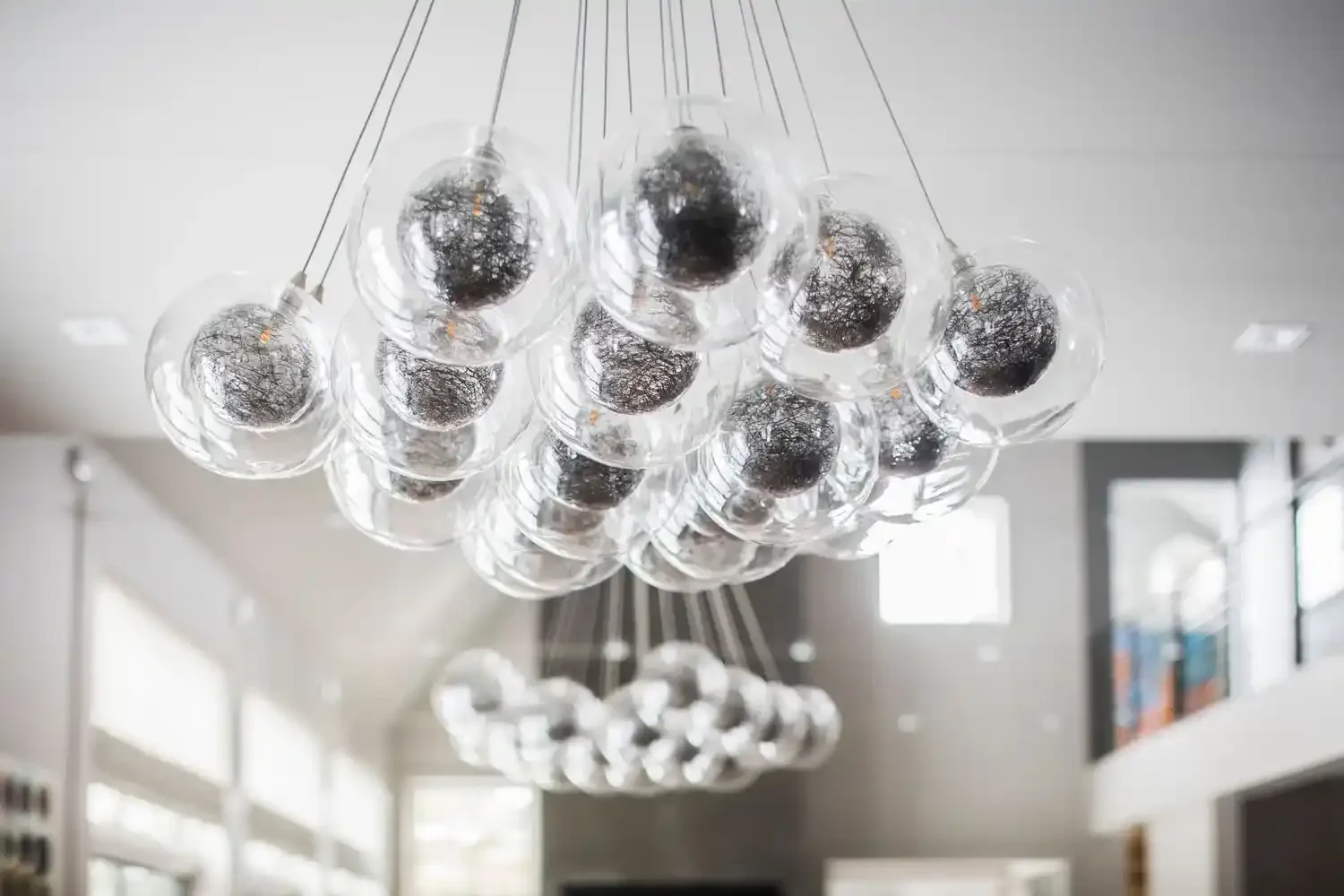 Modern chandelier with multiple glass globes hanging from the ceiling in a bright room.