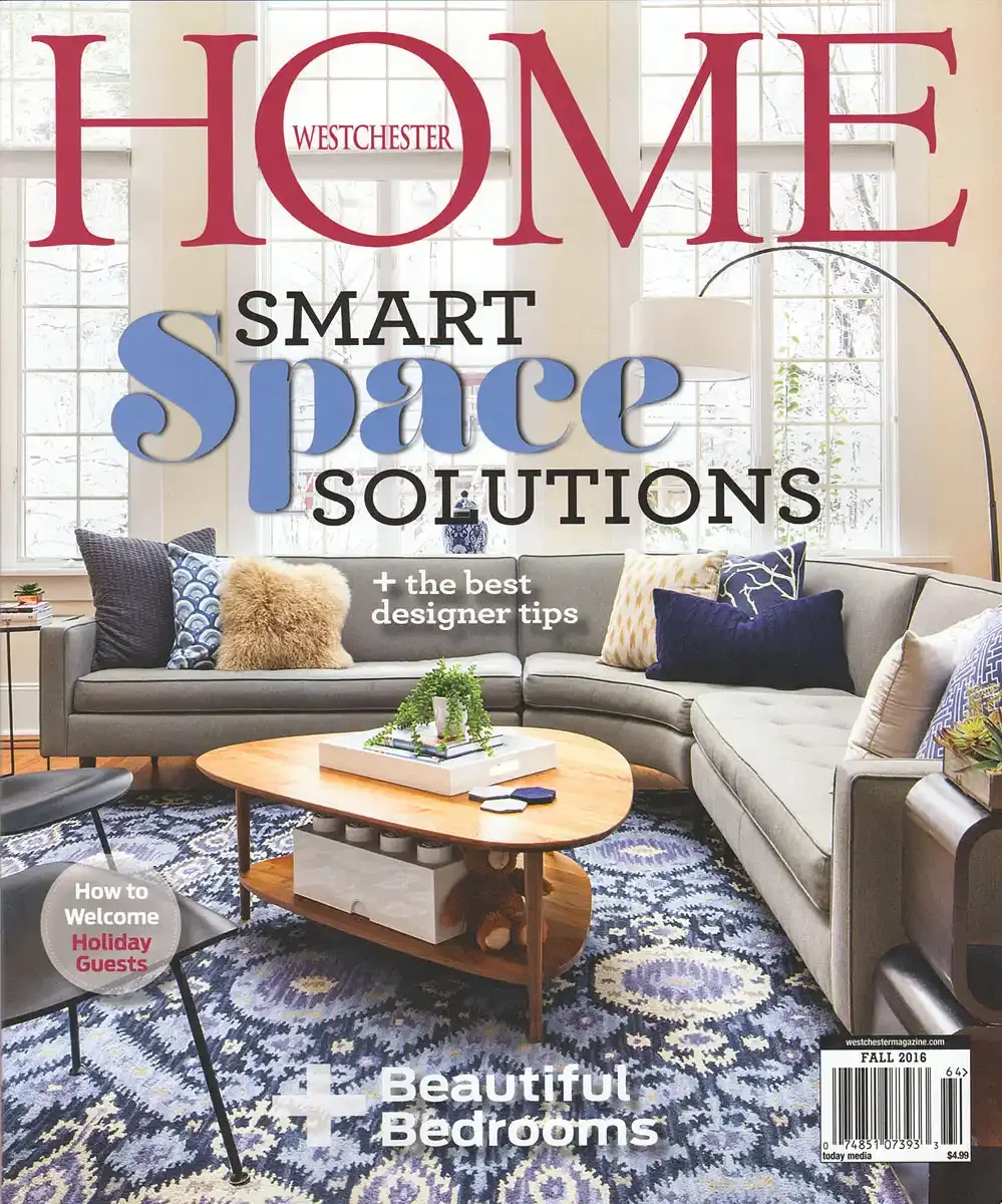 Cover of Westchester Magazine featuring a cozy living room with a gray sectional sofa, various colorful pillows, a wooden coffee table with a small plant, a patterned rug, and large windows in the background.