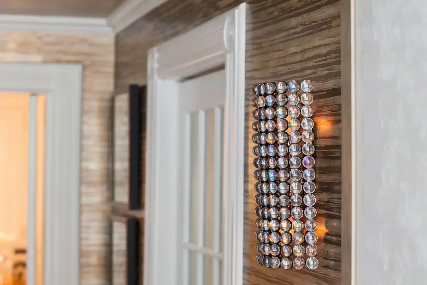 Decorative wall mirror made of multiple small round reflective discs arranged in rectangular pattern on a wooden wall.
