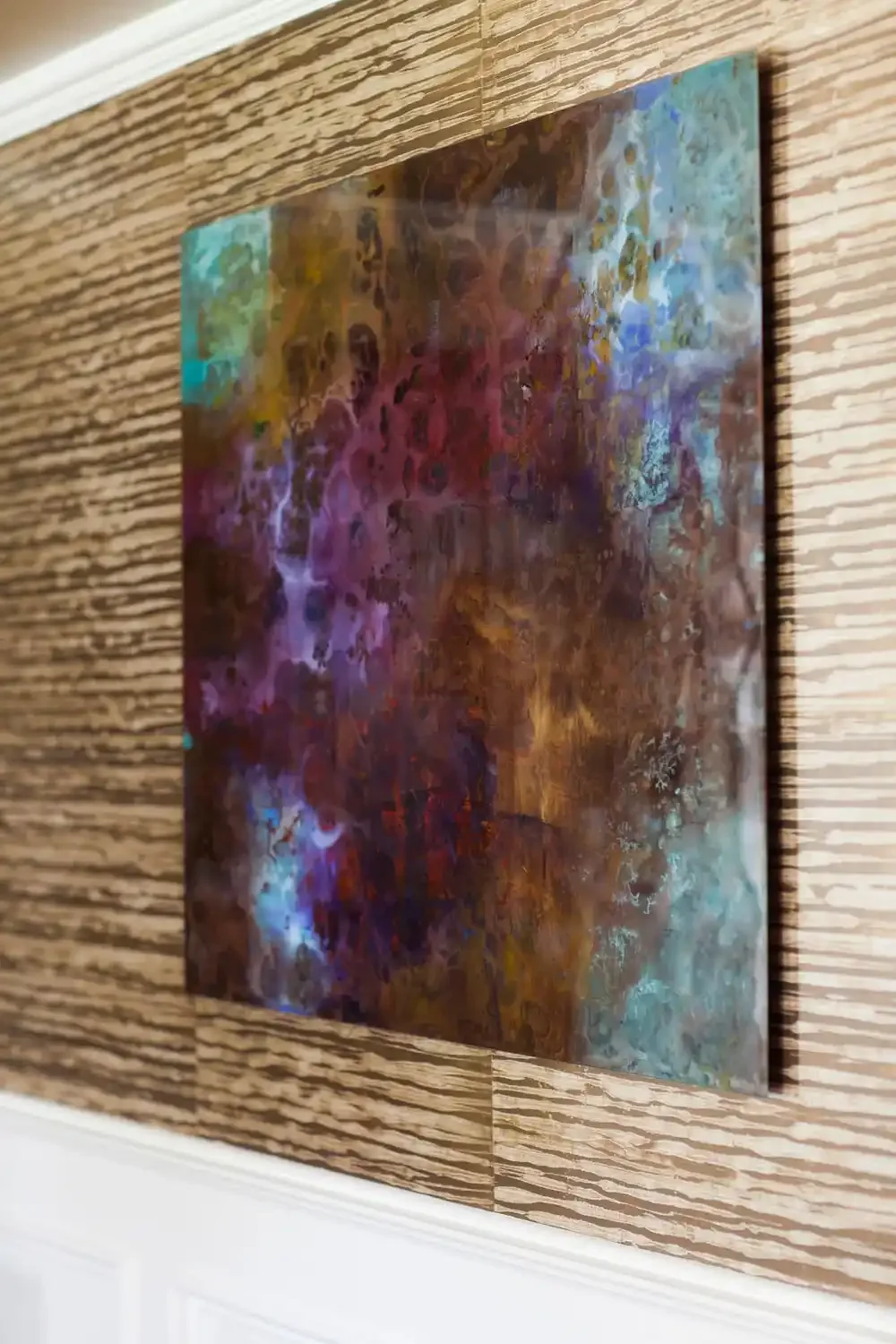 Abstract colorful painting hung on a wooden wall.