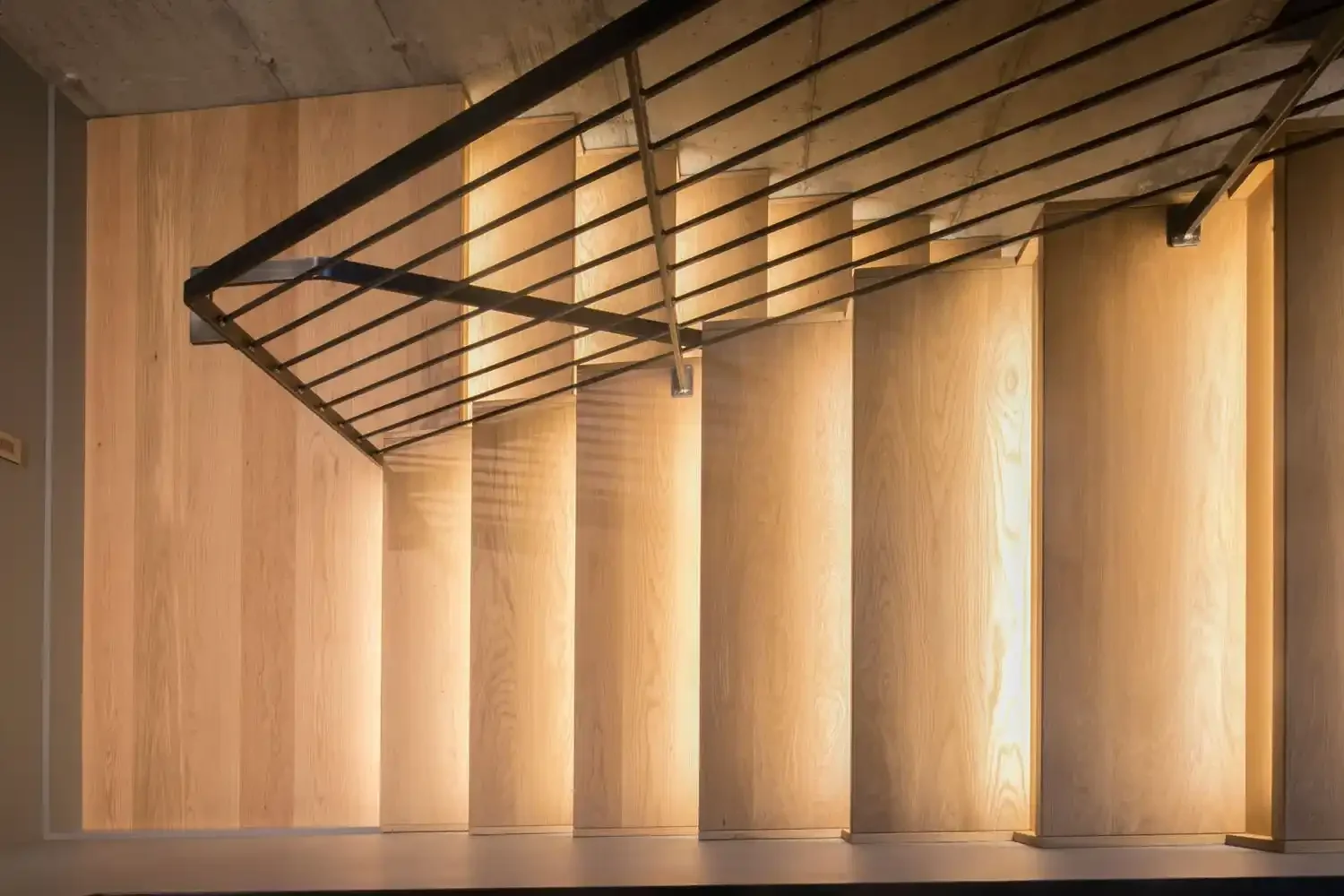 Photo of a modern staircase with wooden steps and a metal railing, viewed from above.