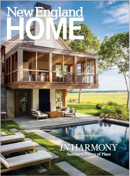 Cover of New England Home magazine featuring an outdoor view of a modern house with a pool, patio furniture, and a lush green landscape under a partly cloudy sky.