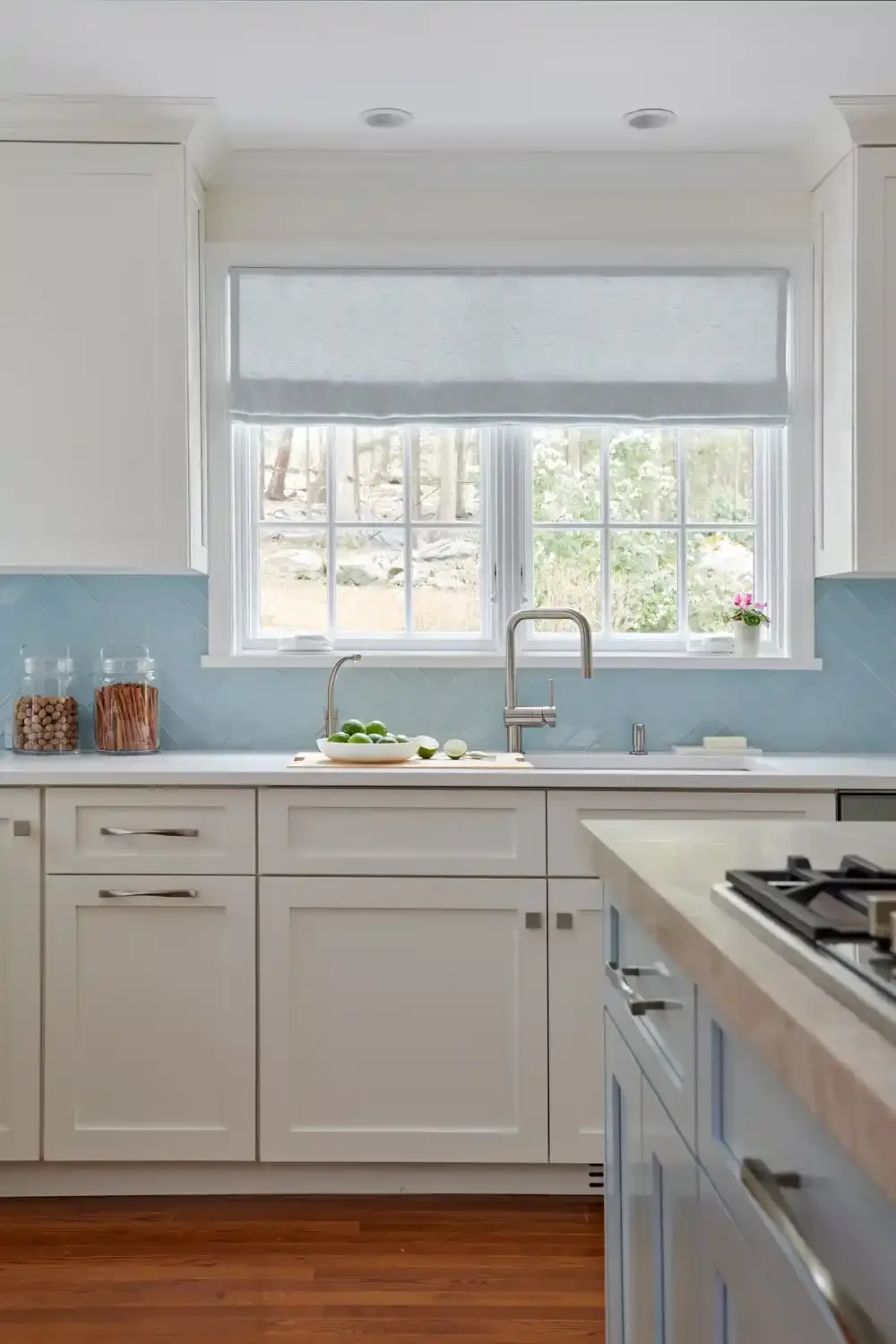 Bright kitchen with white cabinets, a window above the sink, and a bowl of limes on the counter.