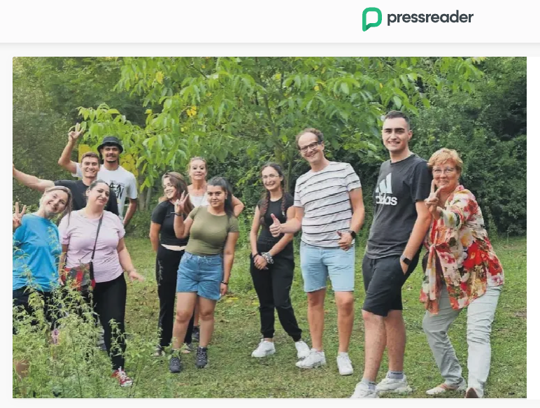 Group of people standing outdoors in a green park, smiling and posing for the photo.