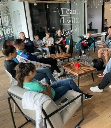 People sitting in a circle indoors, participating in a discussion or group activity.