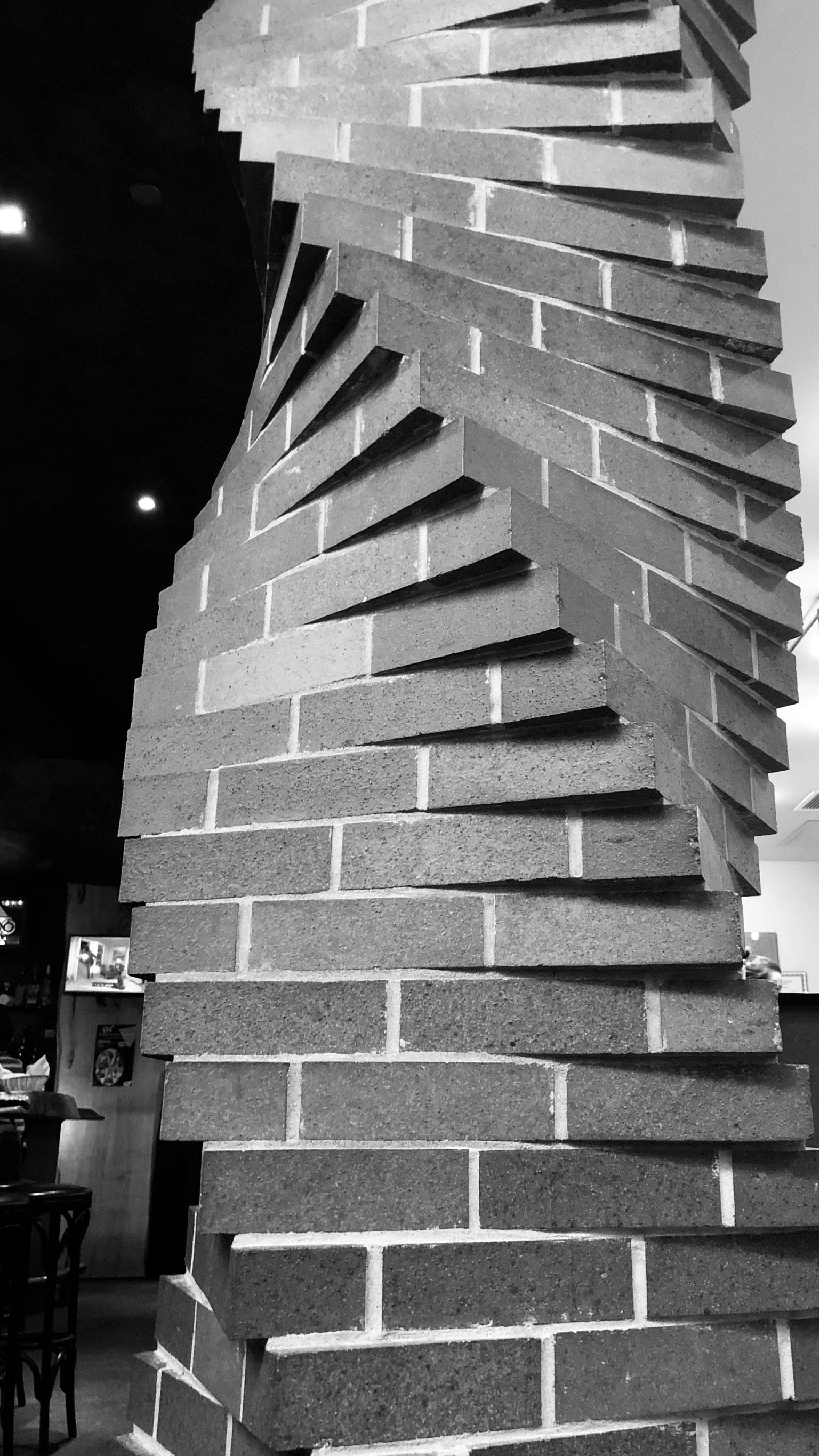 Close-up of a modern brick wall with an artistic, rotating pattern, in black and white.