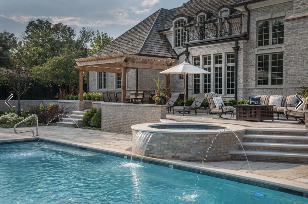Backyard with swimming pool, hot tub, patio furniture, umbrella, and a brick house with large windows and a small balcony.