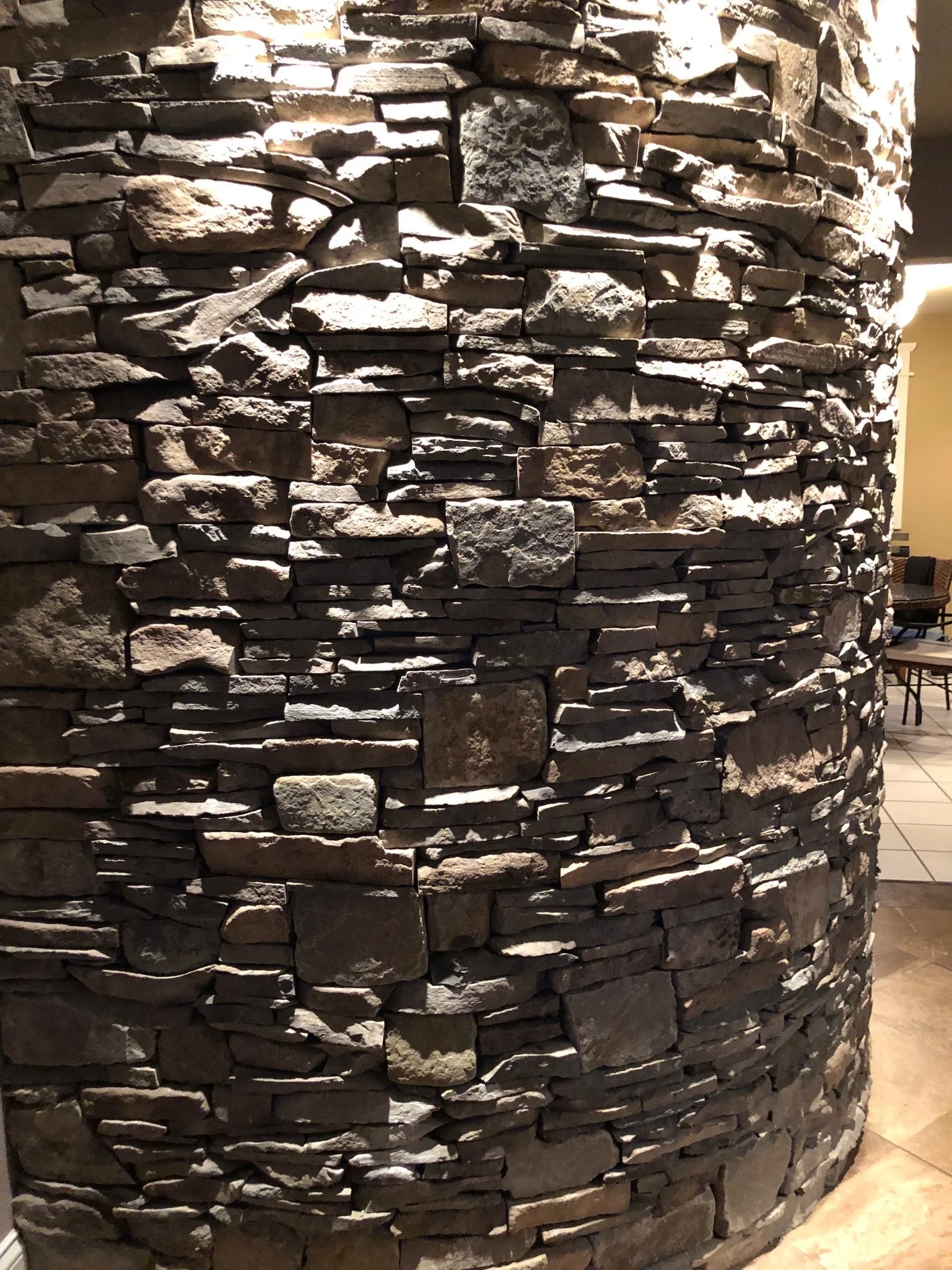 Close-up of a cylindrical stone wall made of stacked flat and irregularly shaped stones.
