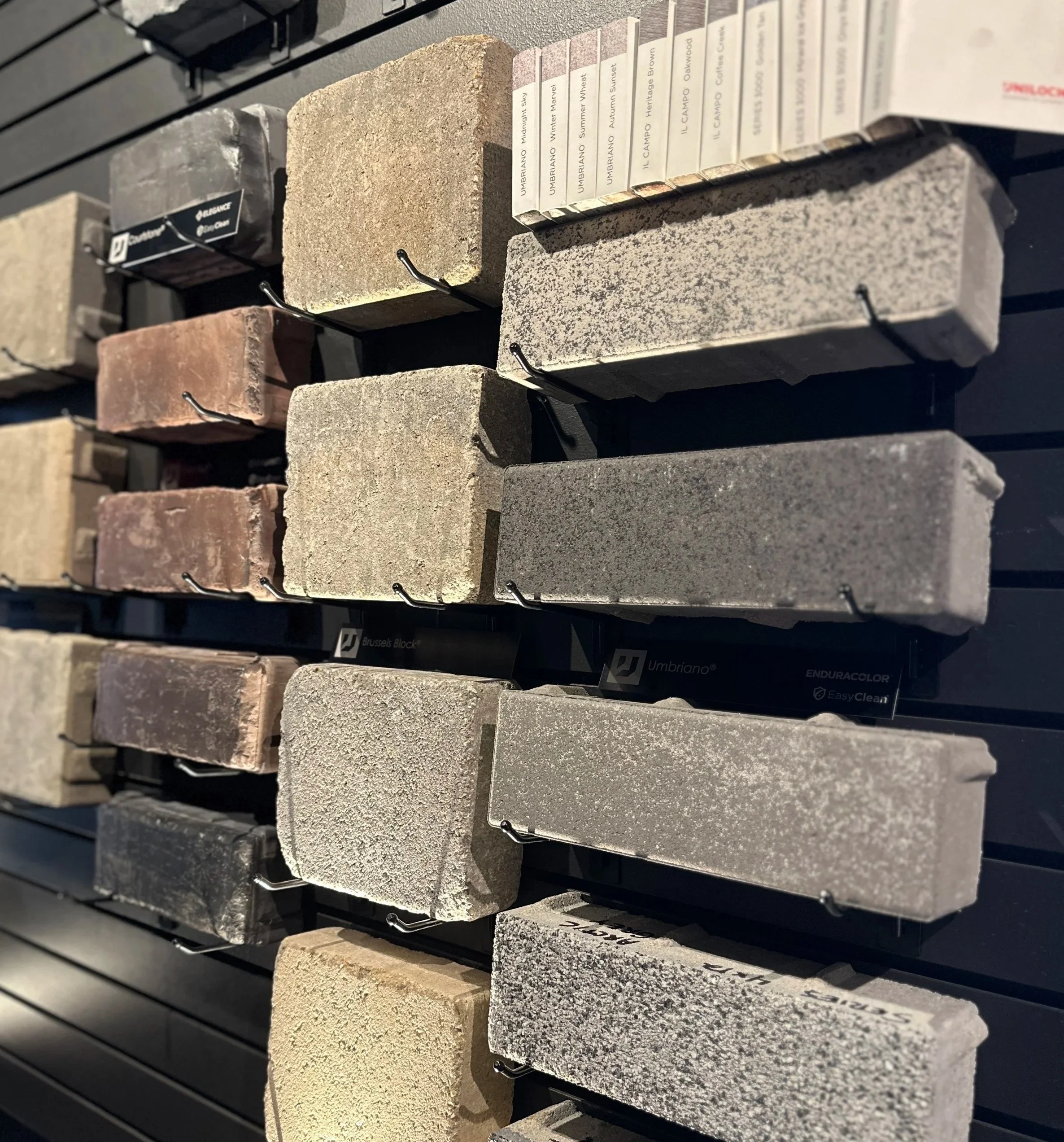 Display of various color and texture stone samples on black metal racks in a home improvement store.