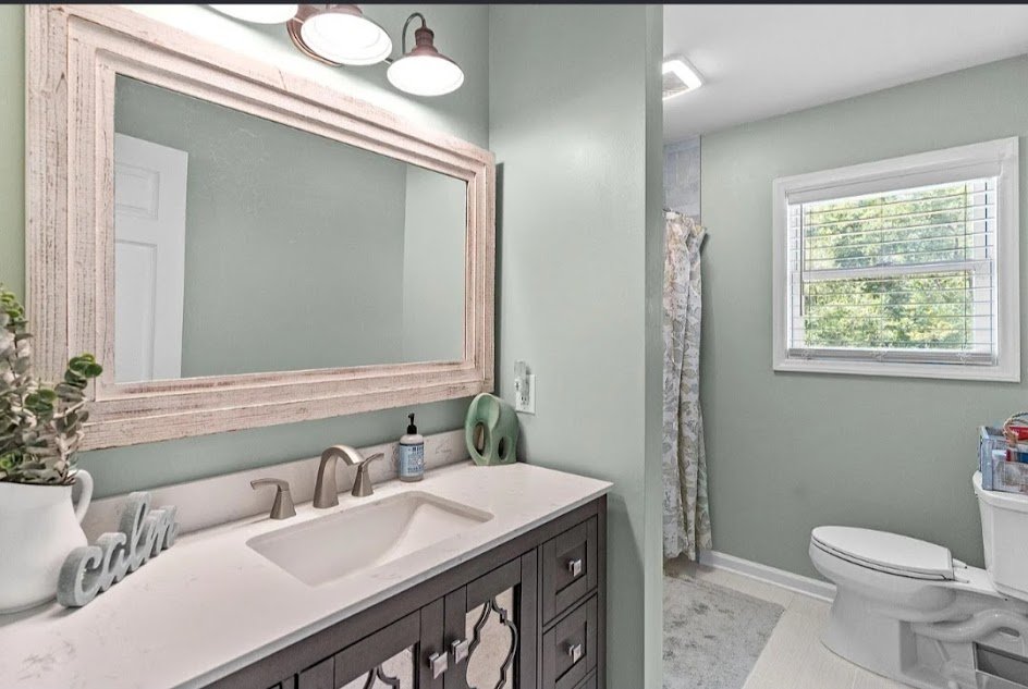 Updated bathroom vanity with white top and mirror. Full-service residential property management in Southport, NC.