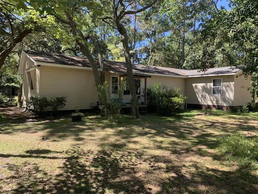Single-family rental house with tan siding and a shaded backyard lawn. Full-service rental property management company in Apex, NC.