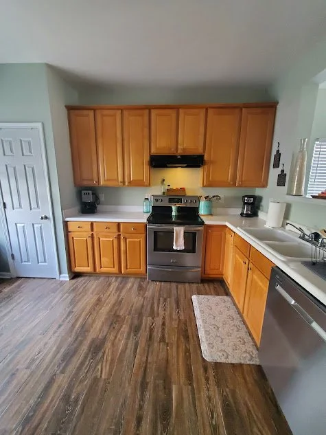  L-shaped kitchen featuring wood cabinets and vinyl plank flooring. Rental property management company in Apex, NC. 
