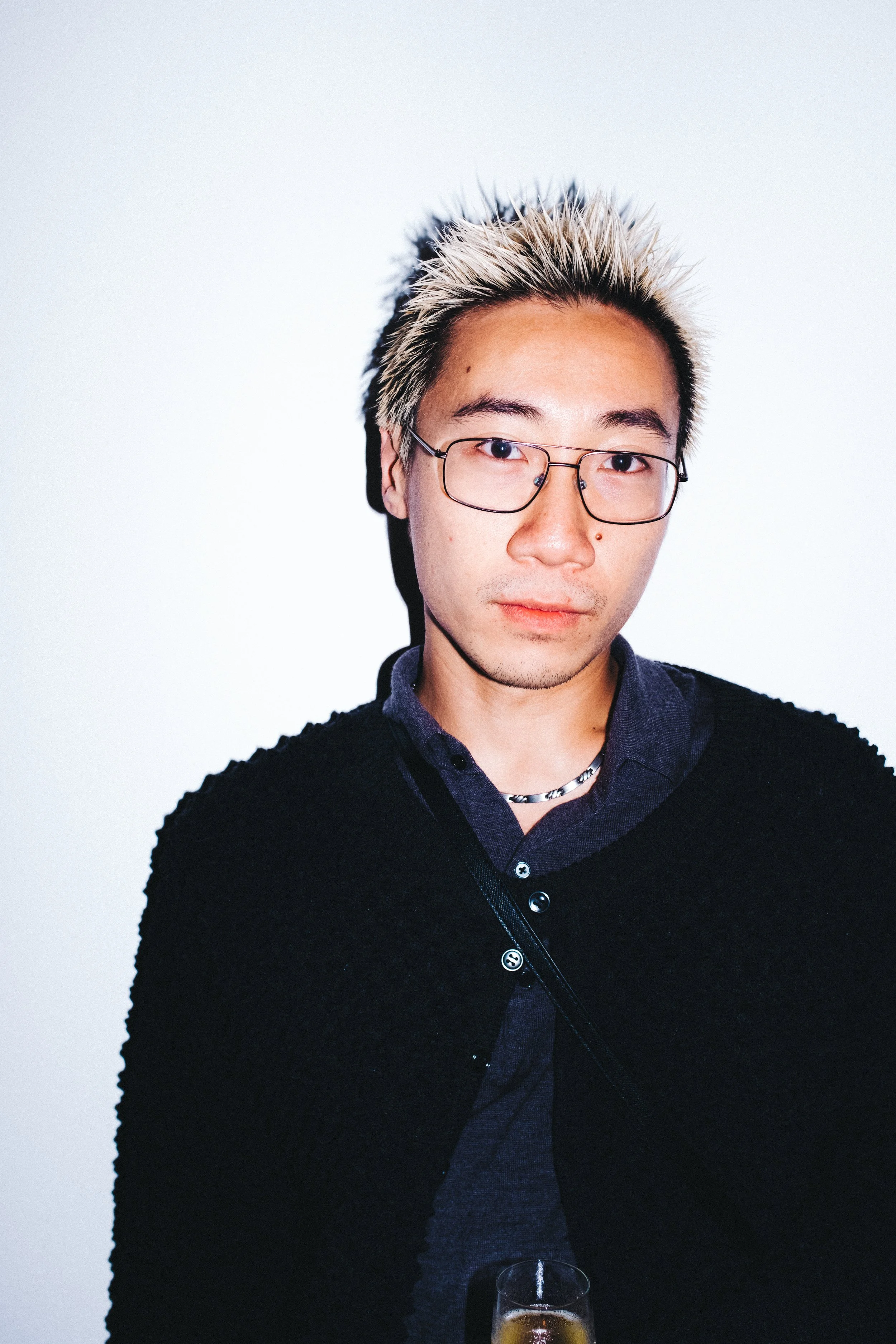 Portrait of designer Chet Lo, a young man with spiky blonde hair and standing against a plain white background.