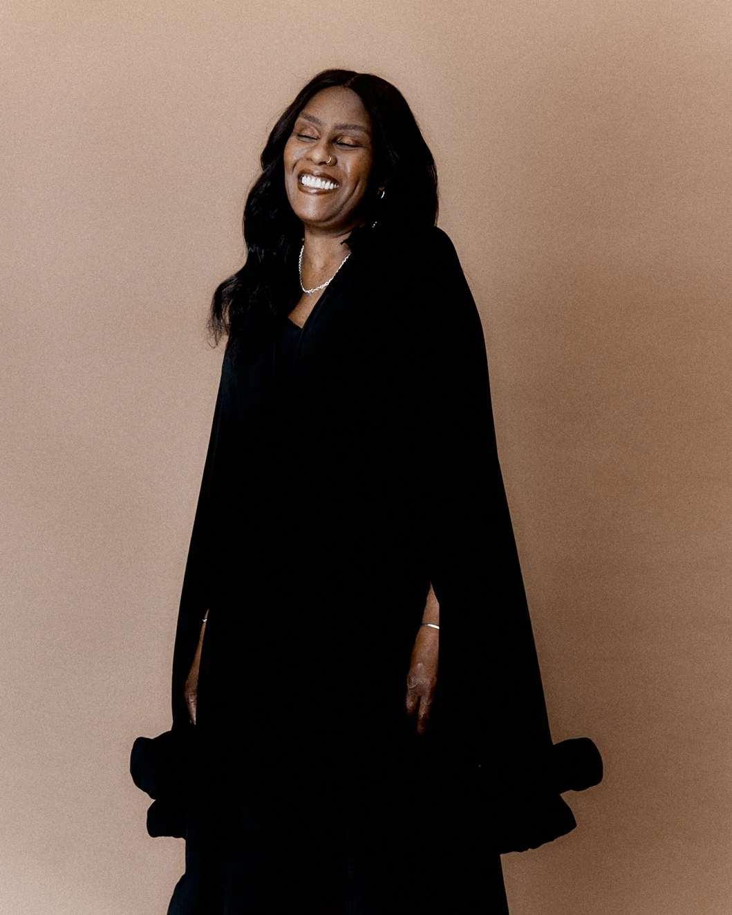  A series of portraits of Grace. She has long black hair and is wearing a long black dress with flared sleeves, silver jewellery, and is standing against a neutral background. 