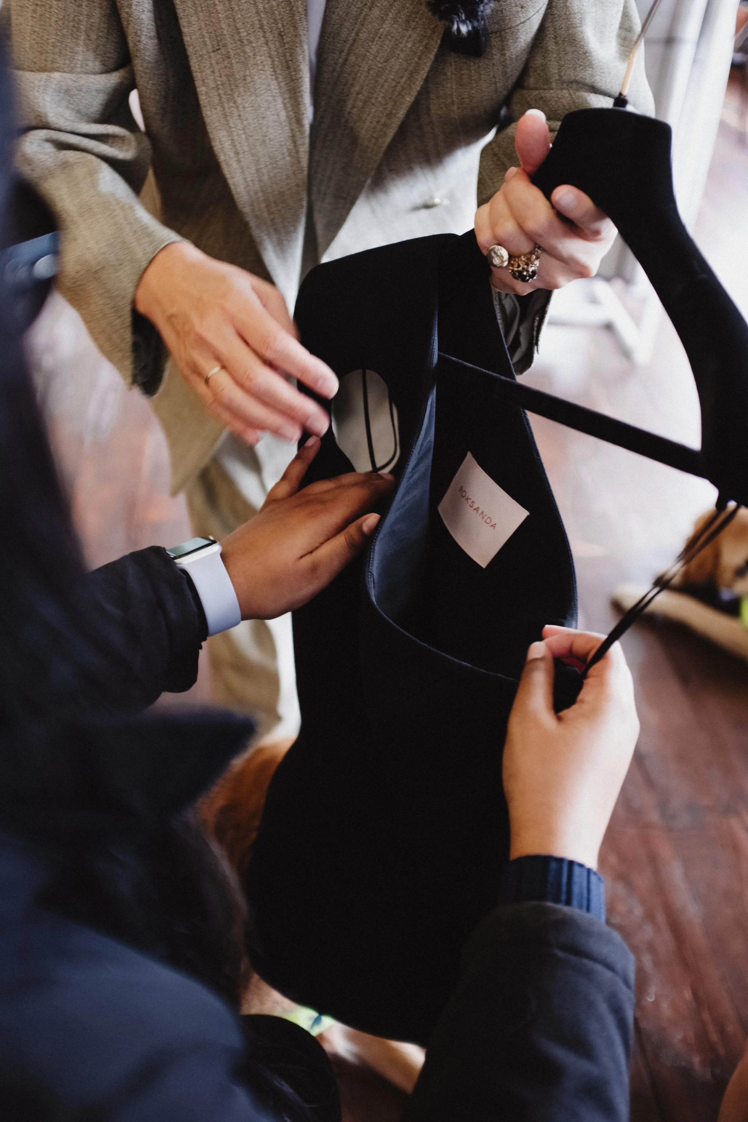 A close-up of hands as they feel a garment displayed on a hanger. Someone guides their hands to different areas of the garment.