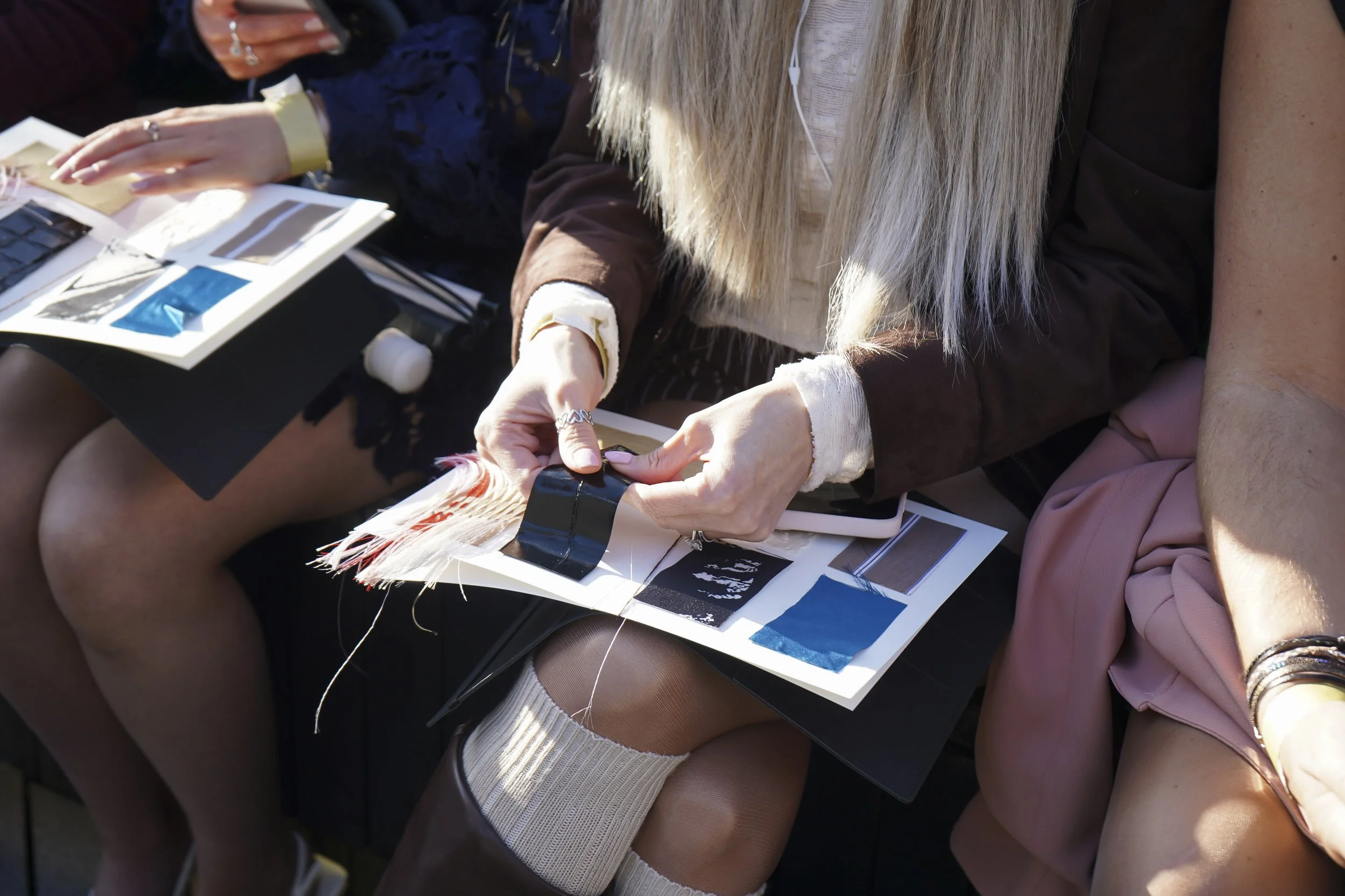 A guest feels fringe and glossy fabric swatches in a tactile booklet on her lap.