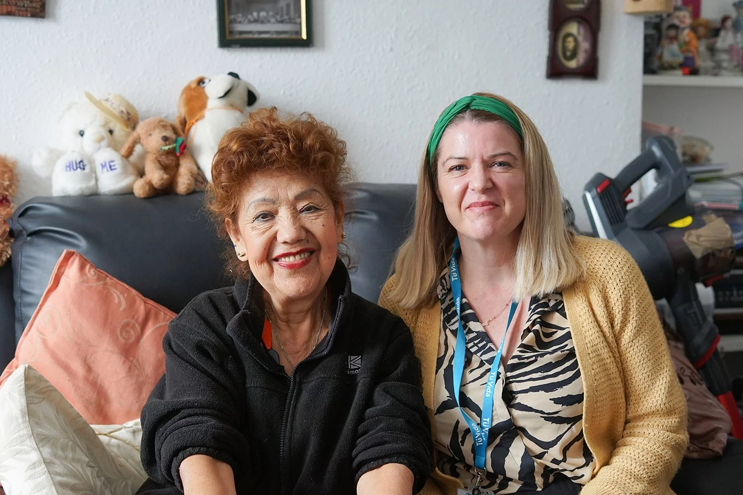 Two woman are sat on a sofa smiling