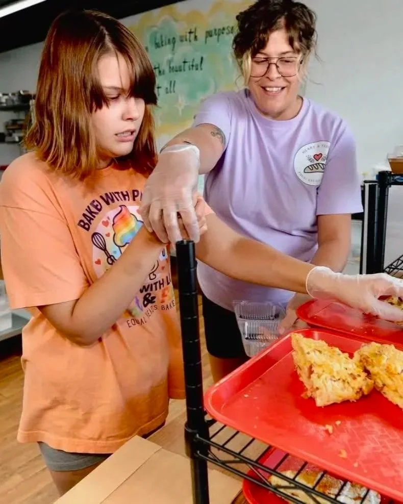 A woman helping a young girl create scones.