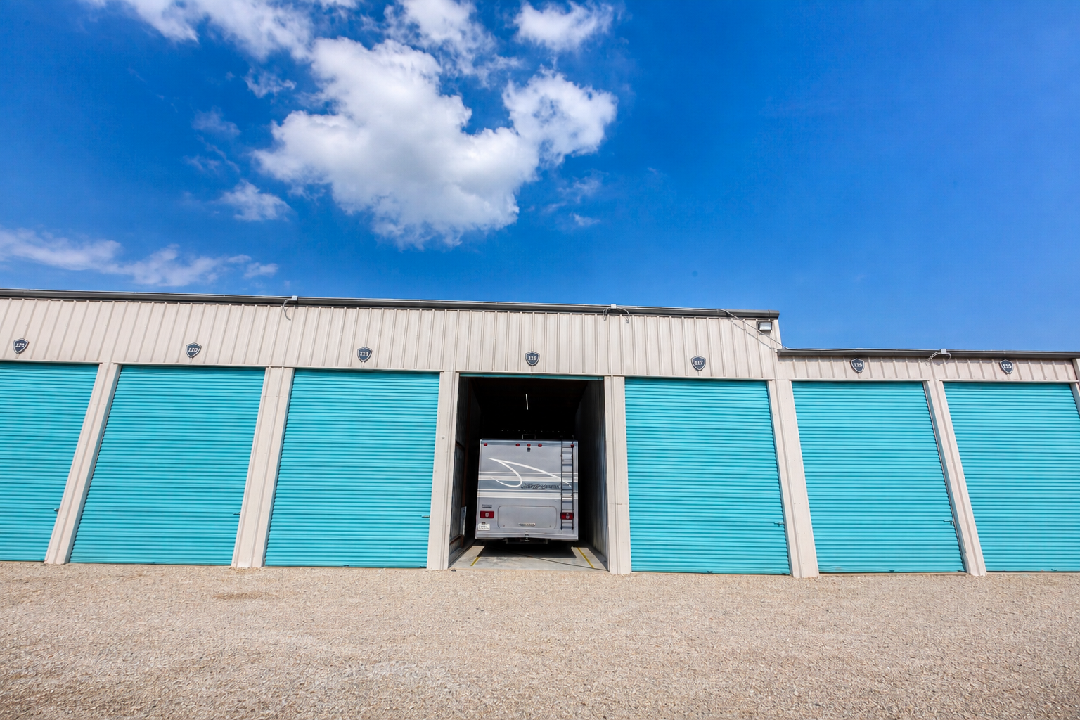 Row of enclosed RV storage units with a motorhome parked in an open bay at Carefree Enclosed Boat & RV Storage, Wylie, TX