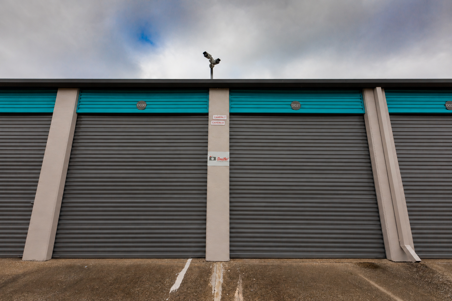 Row of enclosed RV and boat storage unit doors with a security camera at Wylie Bargain Storage in Wylie, TX