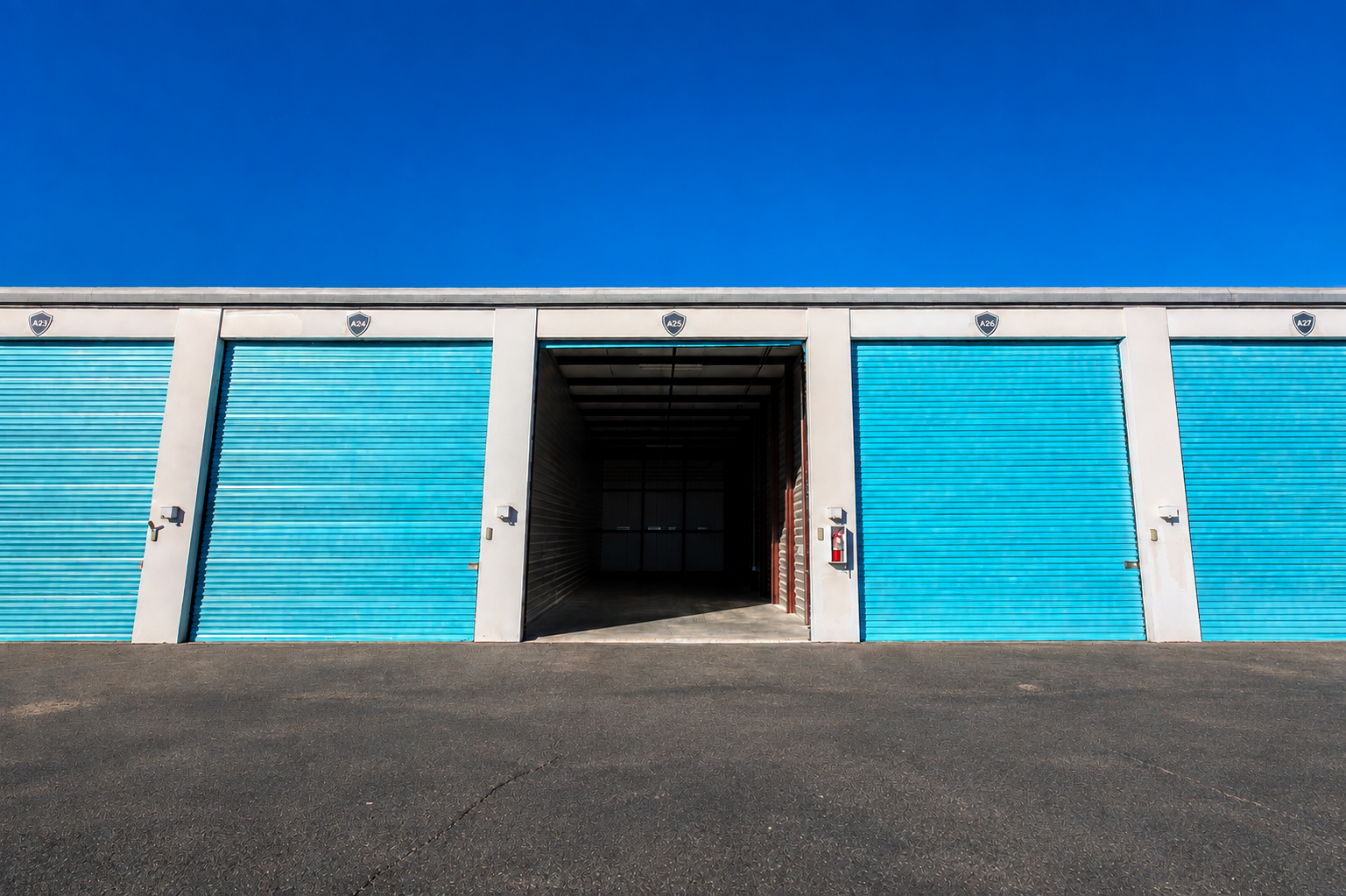 Row of enclosed RV garage unit doors with one door open at Carefree Covered RV Storage in Chandler, AZ