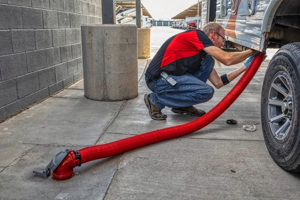Customer connecting a sewer hose to an RV at the free dump station at Carefree Covered RV Storage's Chandler Kyrene Rd location