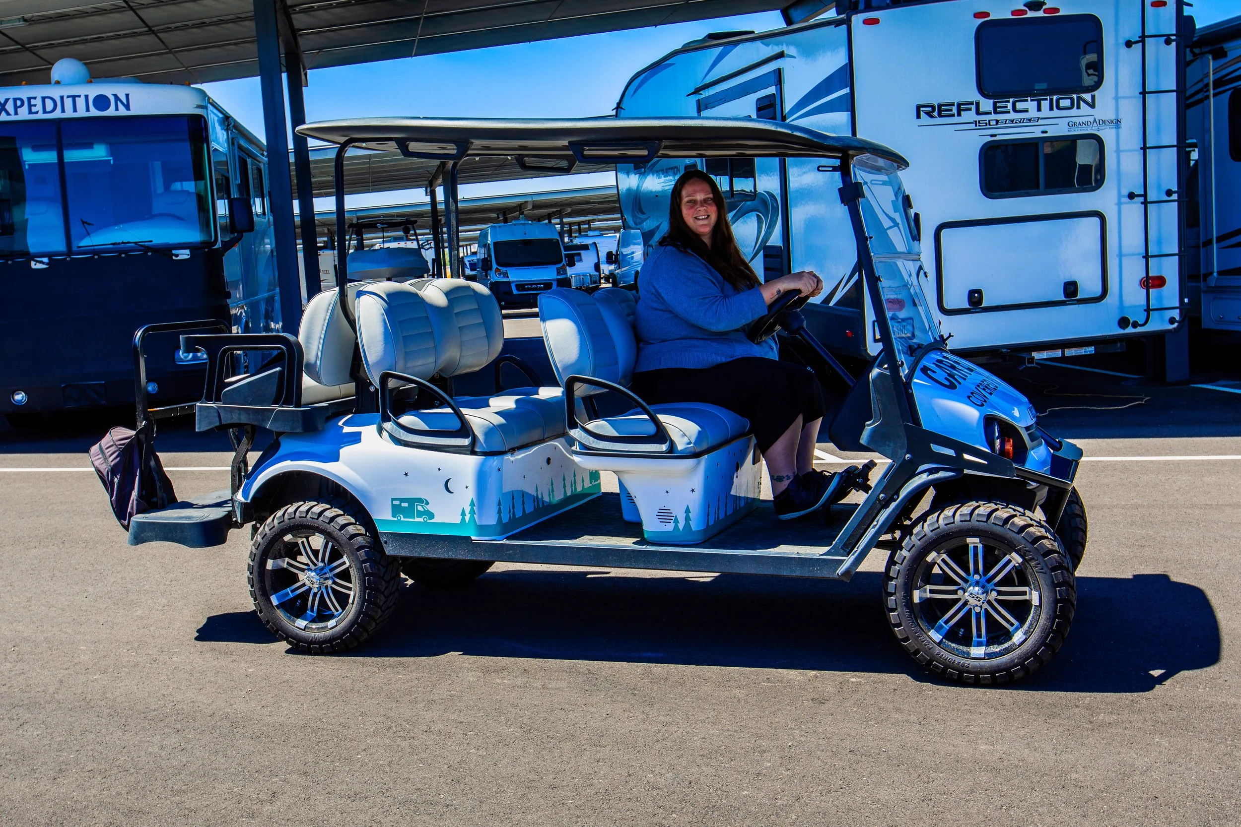 Property manager driving a branded golf cart between Carefree Covered RV Storage lots on Kyrene Rd, Chandler AZ