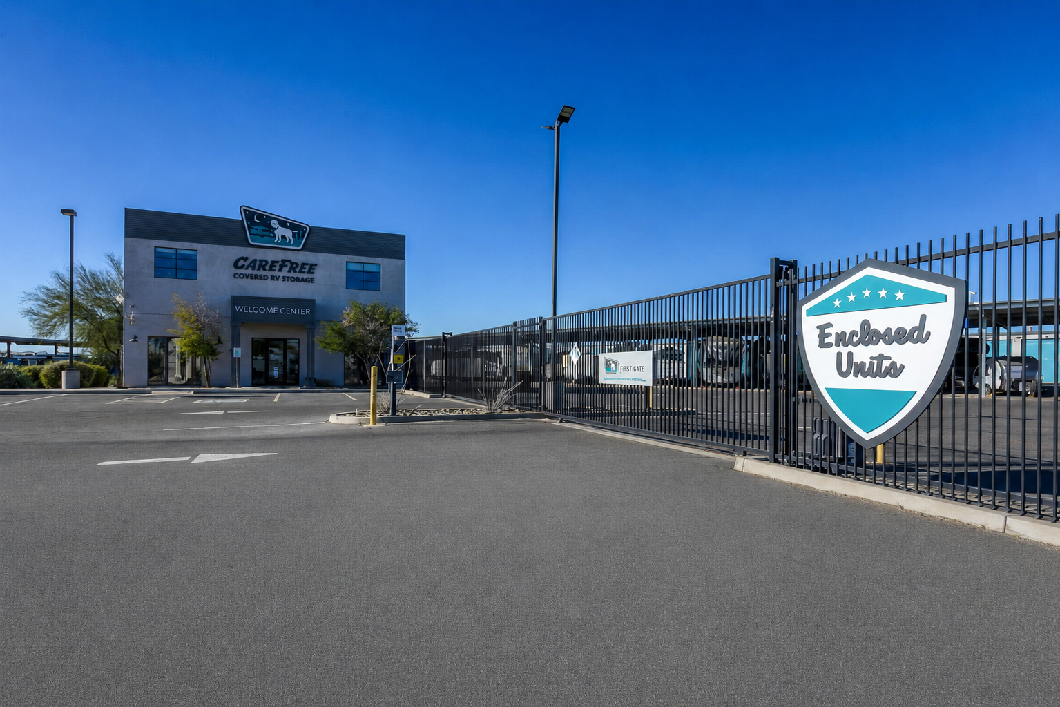 Gated entrance to Carefree Covered RV Storage in Chandler, AZ, with an Enclosed Units sign mounted on the security fence and the welcome center building in the background