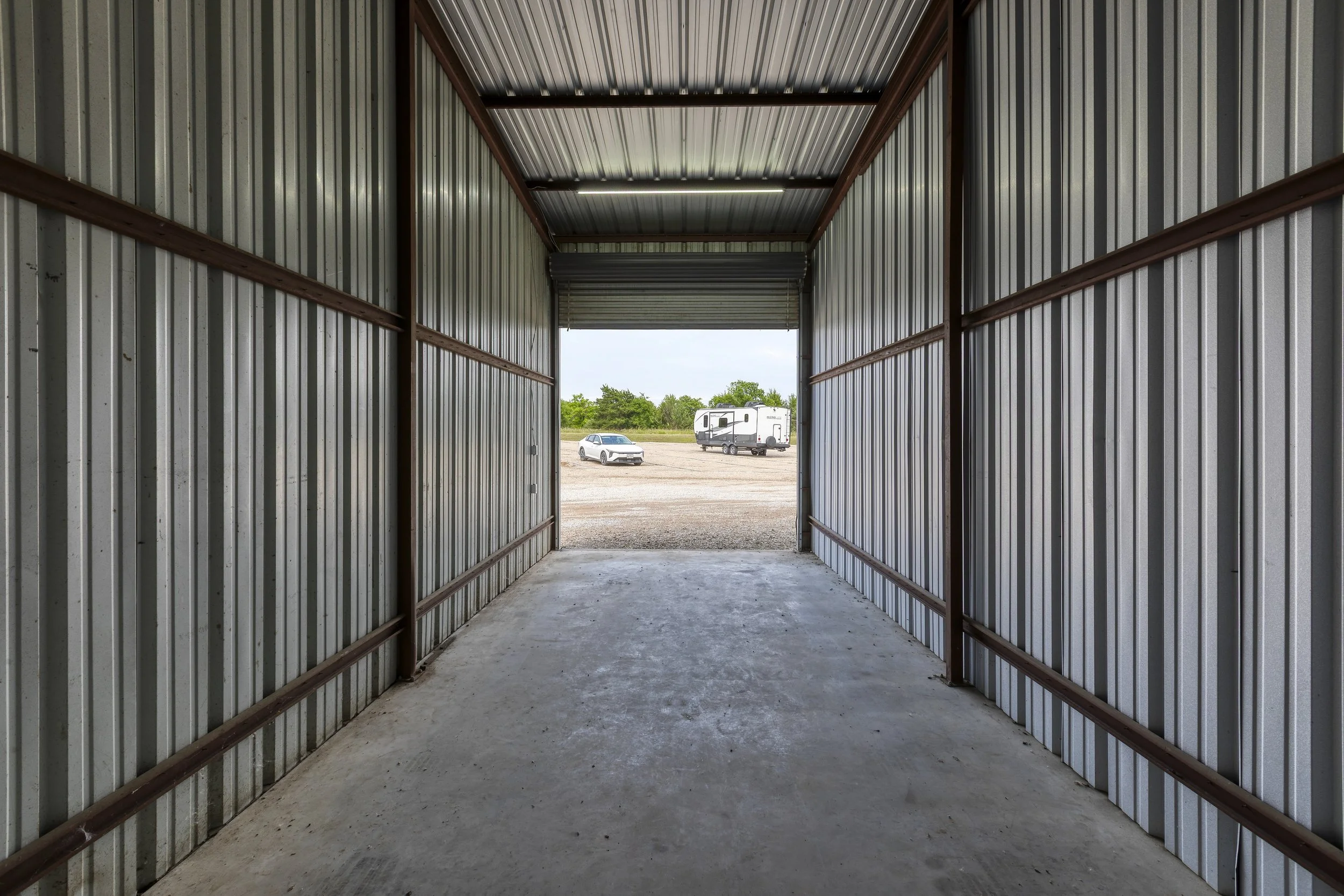 Empty enclosed RV storage unit interior with metal walls and overhead lighting at Carefree's Wylie, TX facility