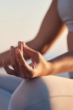 Close-up of a person meditating with fingers resting in a relaxed mindfulness mudra.