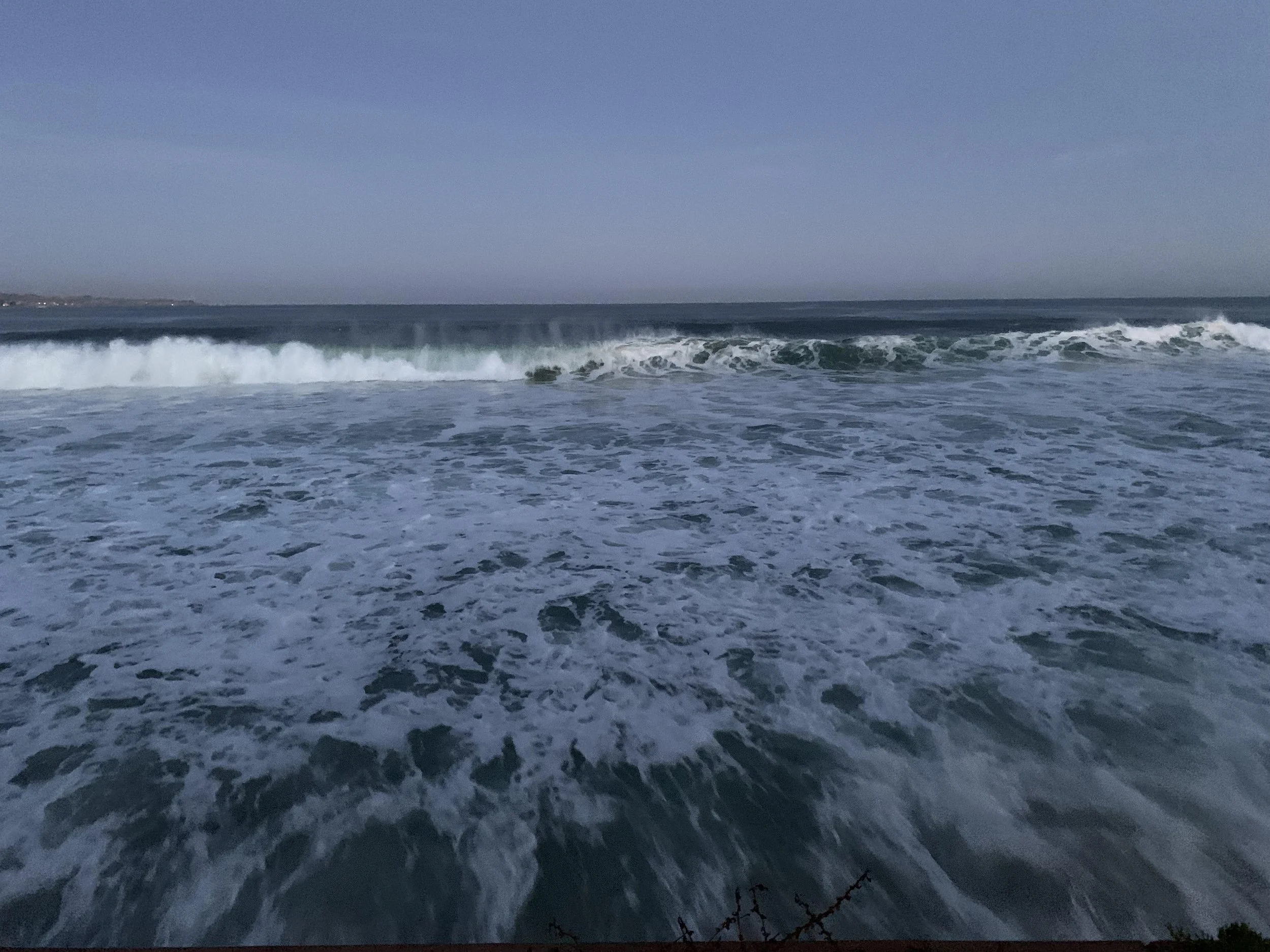 Ocean waves crashing onto the shore on a clear day.