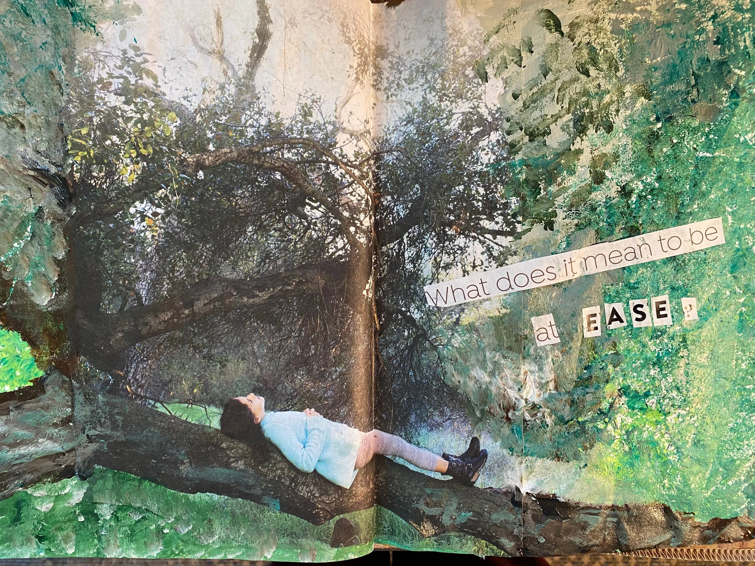 A girl in a white hoodie and jeans leaning against a tree trunk in a lush green forest.