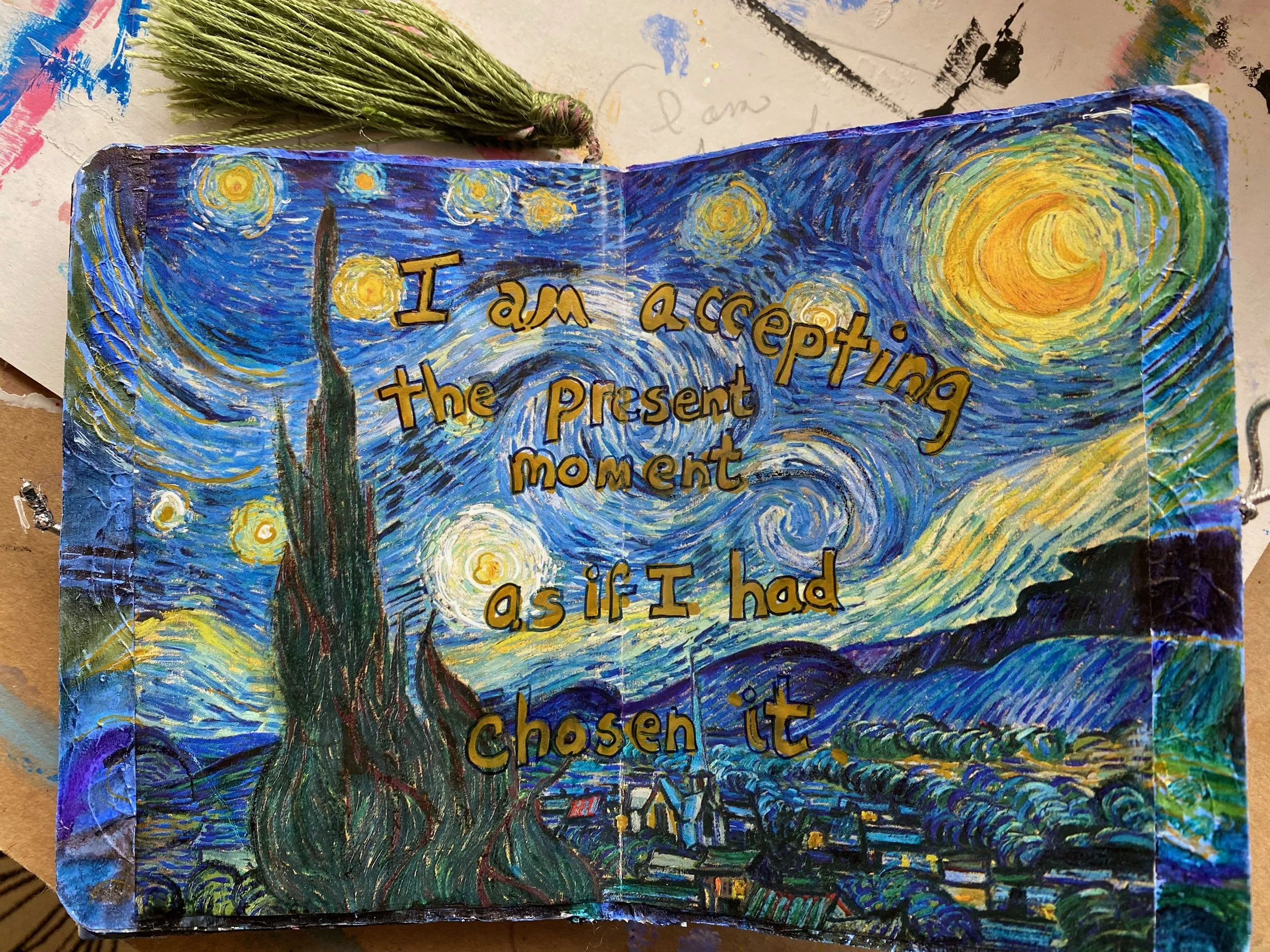 A colorful, painted card features a starry night sky with swirling patterns. The words 'I am accepting the present moment as if I had chosen it' are written over the scene.