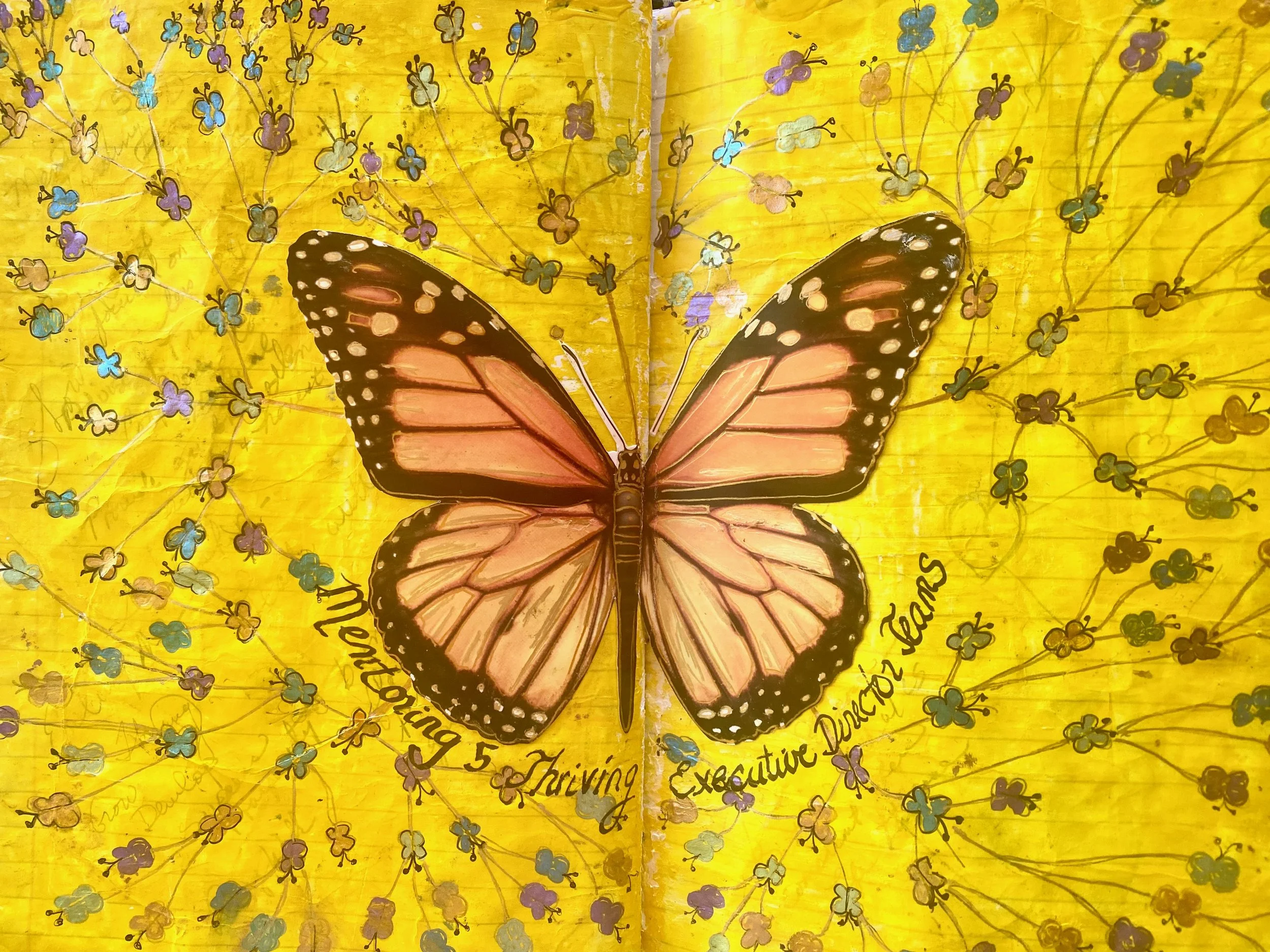 A butterfly with orange and black wings with white spots on a yellow background decorated with tiny multicolored flowers.