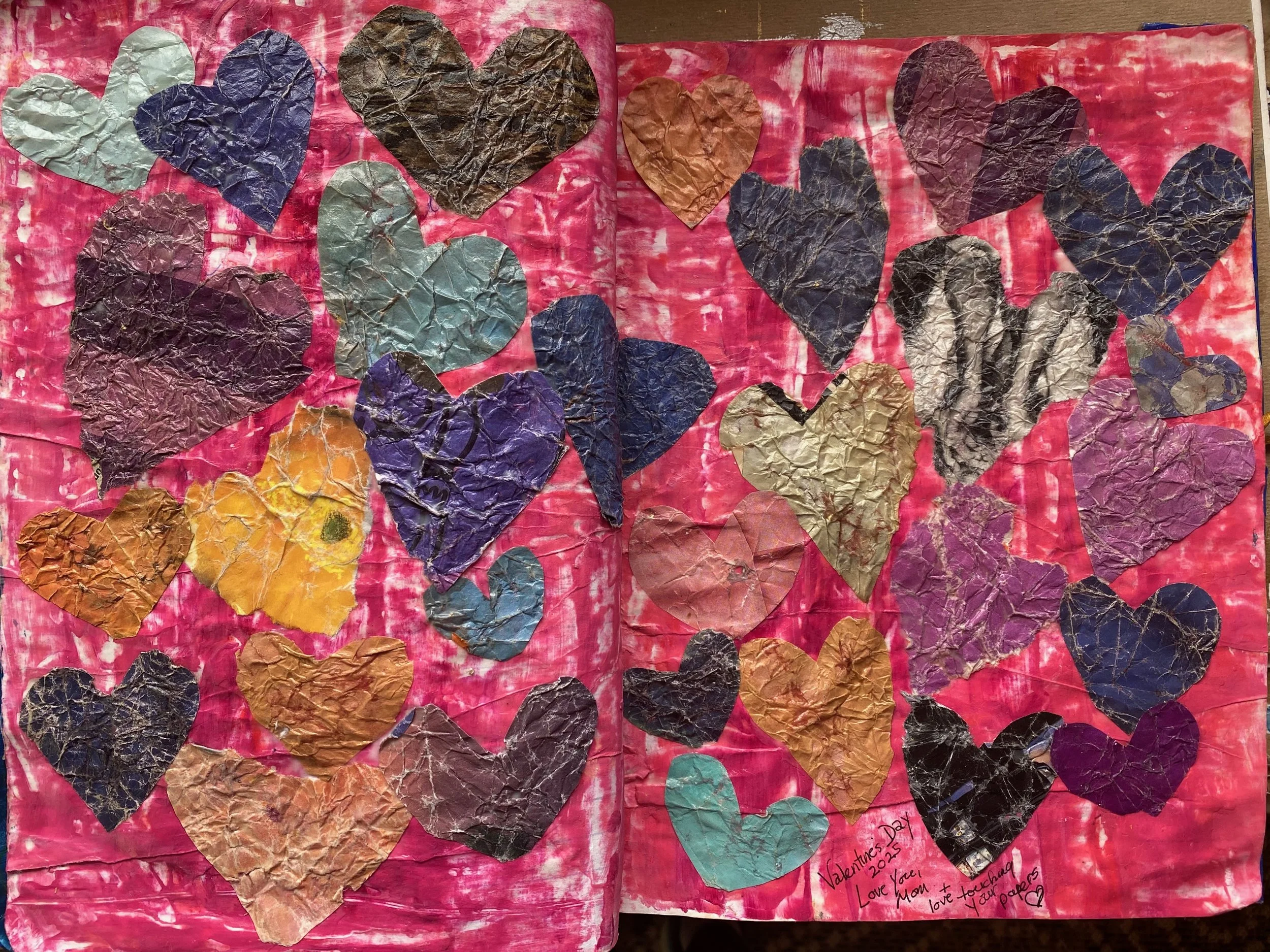 A collection of colorful paper hearts on a pink painted background, with a handwritten note about Valentine's Day from a mother to her children.