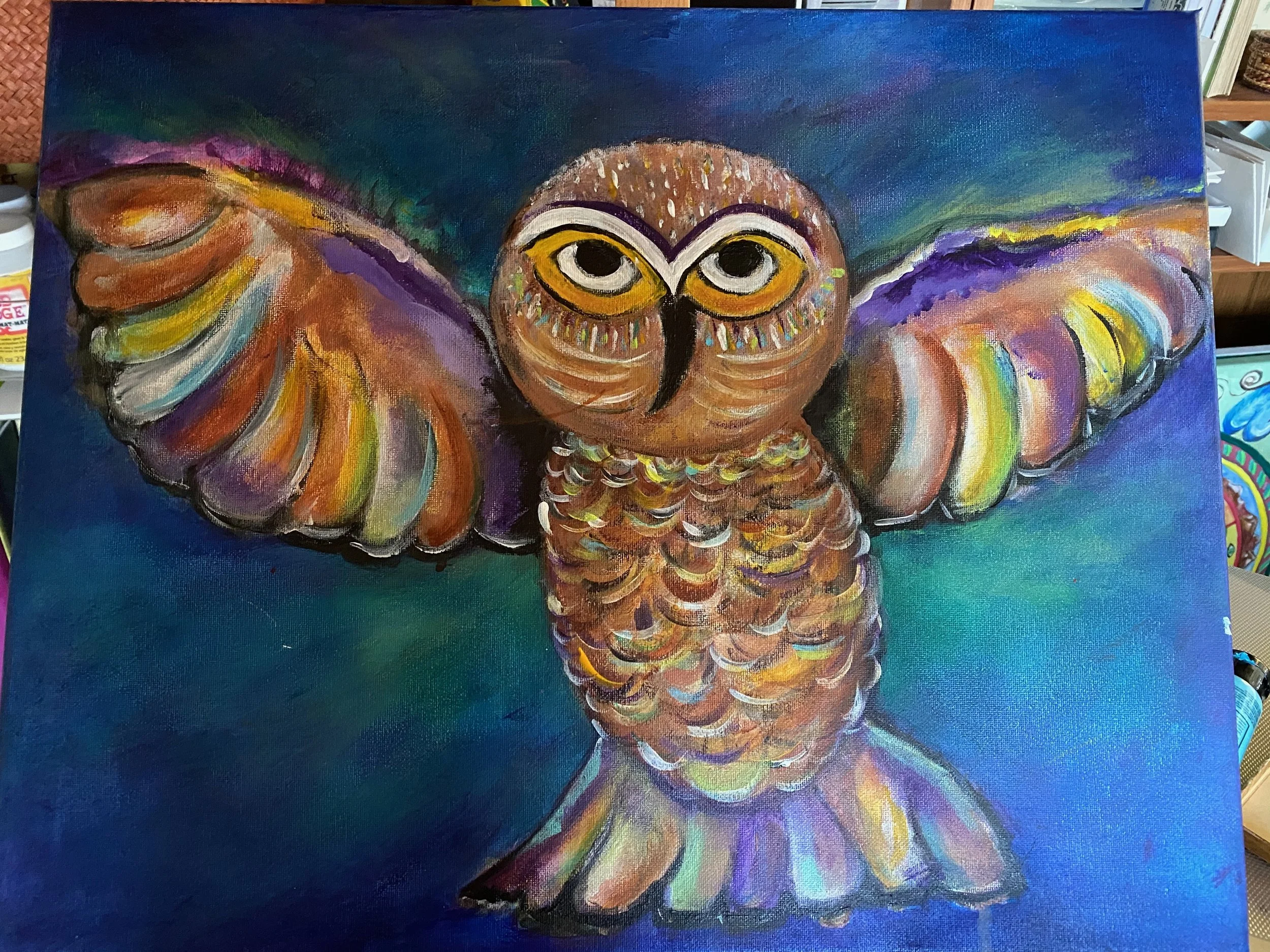 A colorful painted artwork of an owl with wide eyes and outstretched wings against a dark blue background.