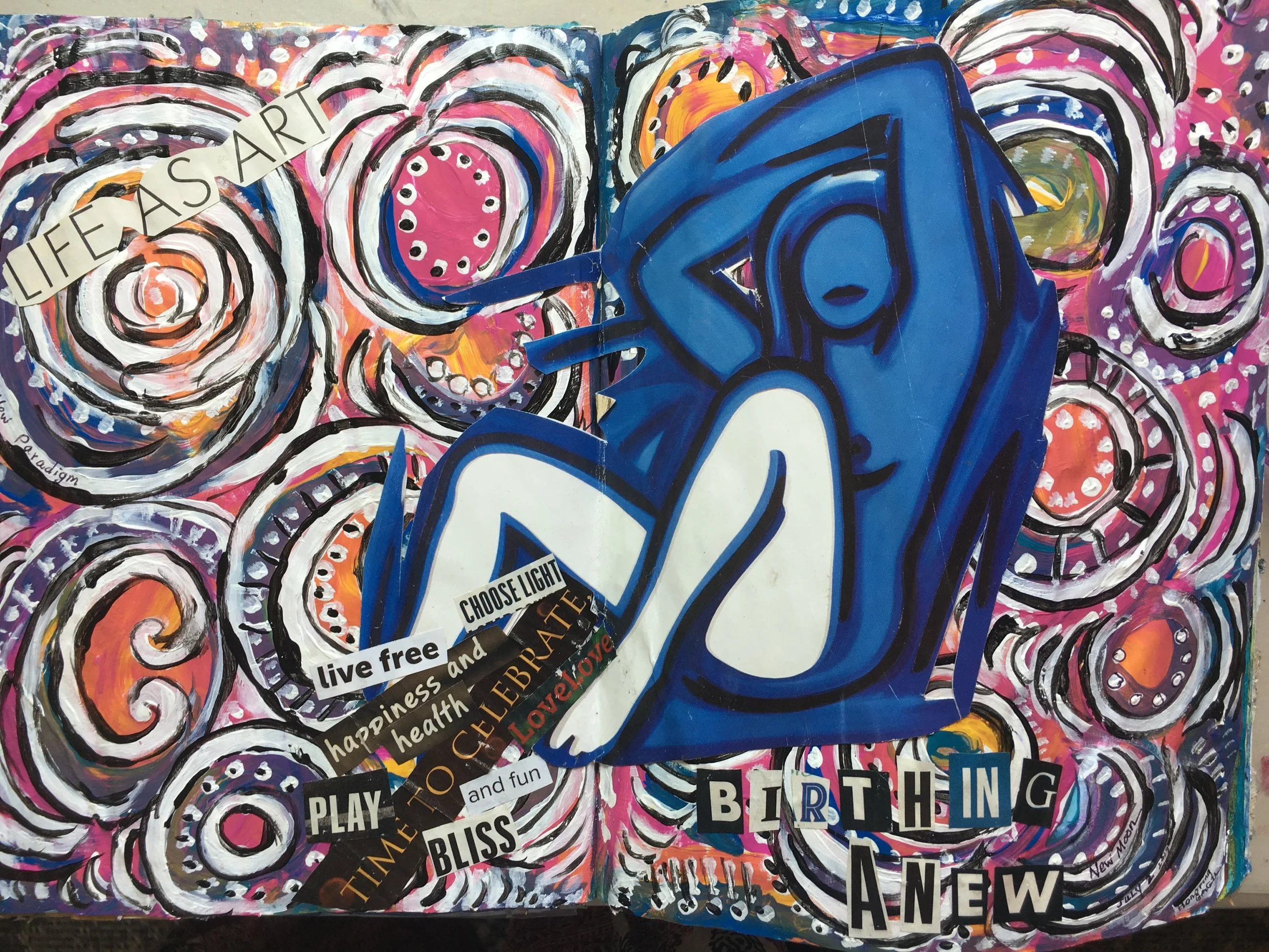 Colorful abstract painting with swirling patterns and various words related to celebration, such as 'LIVE FREE,' 'HAPPY,' 'BIRTHDAY,' and 'NEW,' arranged in collage style.