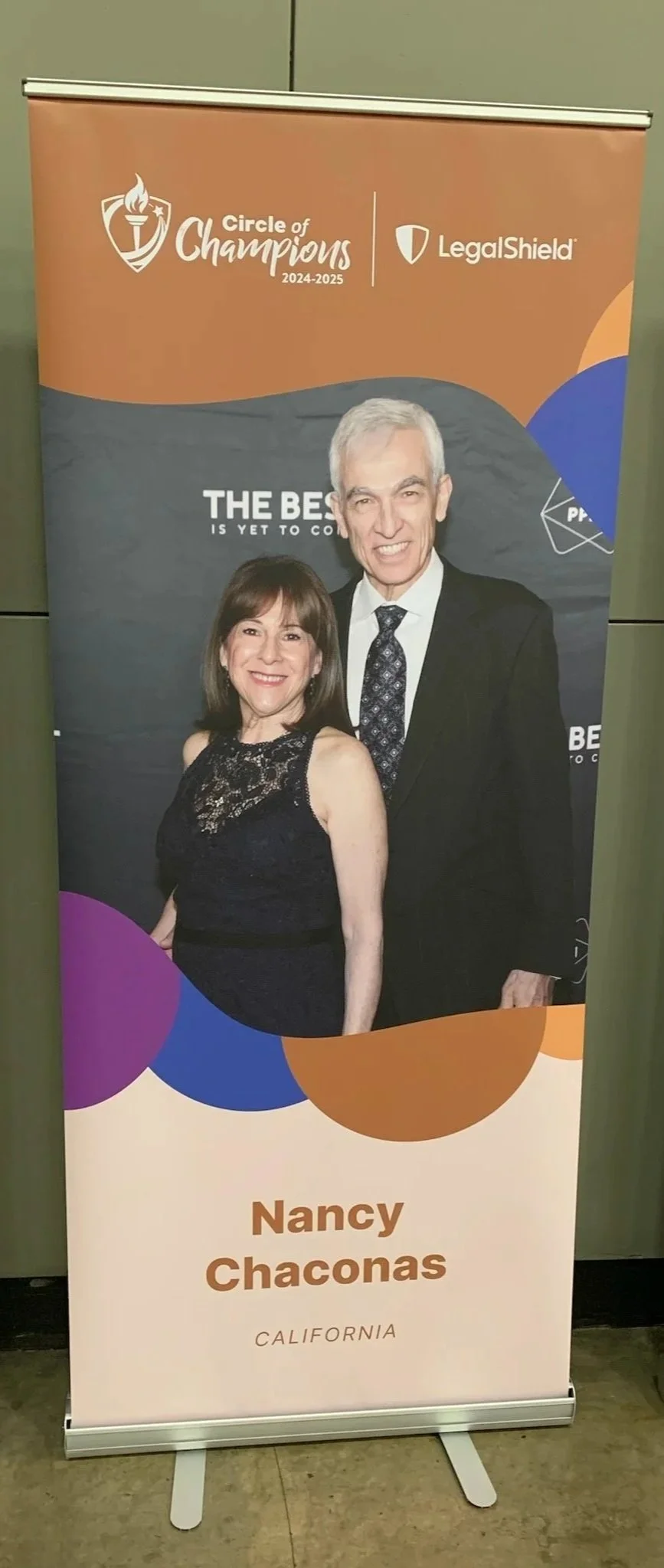 A vertical banner featuring a man and woman dressed in formal attire, with the text 'Nancy Chaconas' and 'California' at the bottom. The banner has a background with colorful circles and displays logos for 'Circle of Champions' and 'LegalShield' at the top.